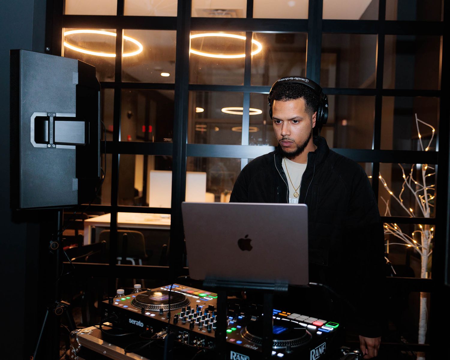 DJ performs at night club with professional equipment and lighting setup in dark atmospheric setting.