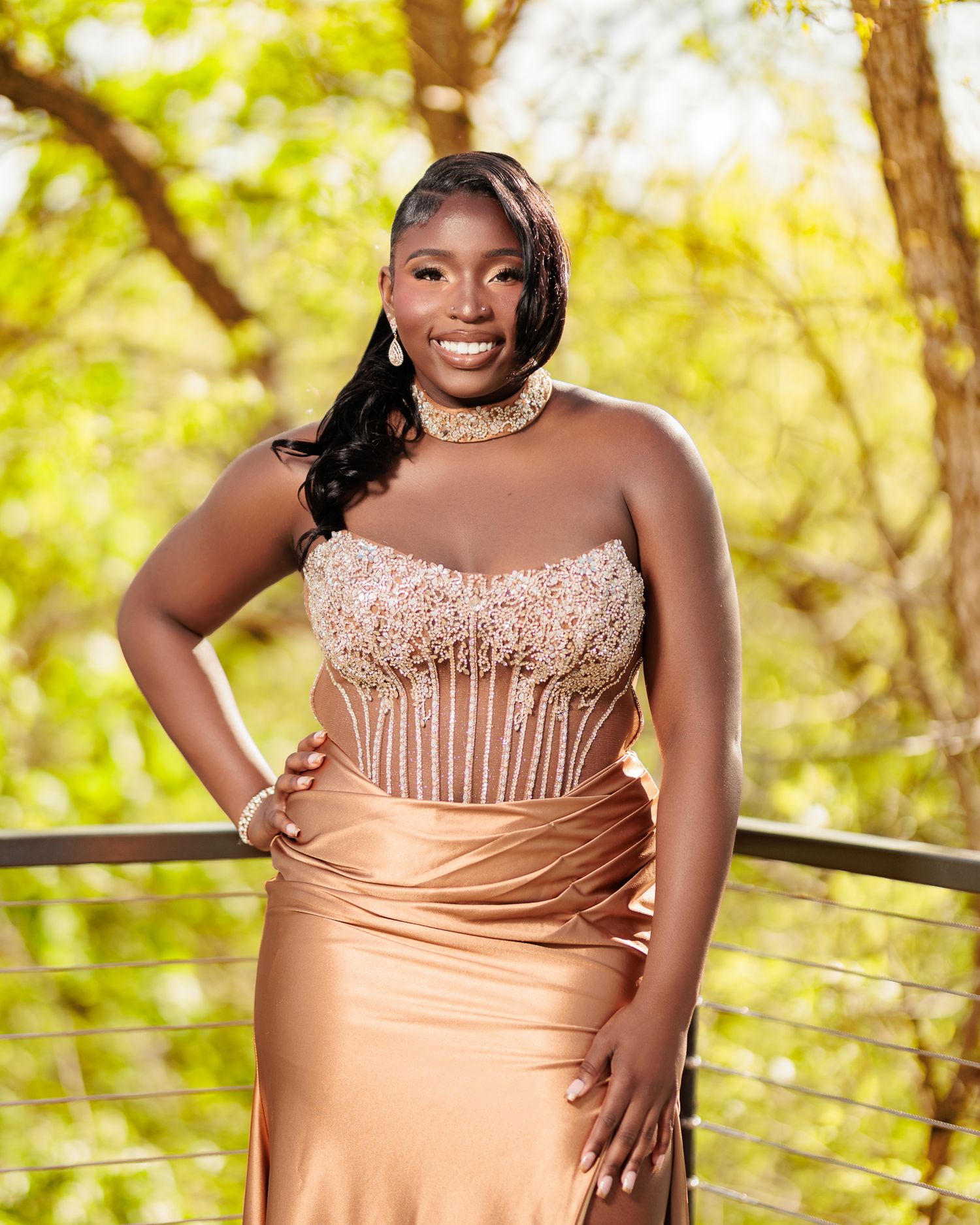 Young woman in elegant rose gold strapless gown with beaded bodice posing outdoors at a formal event.