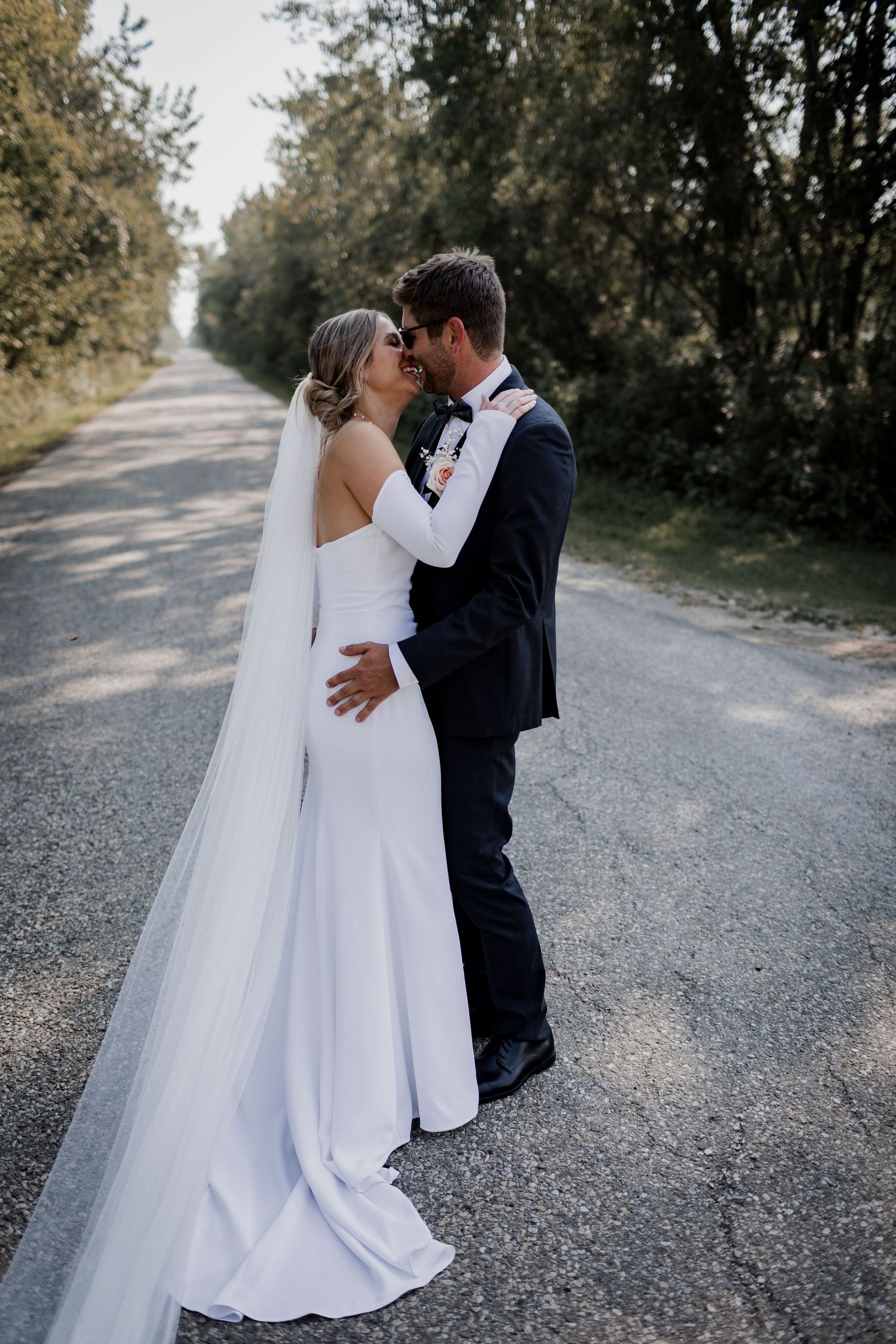 Couple in wedding attire shares intimate moments on a gravel path.