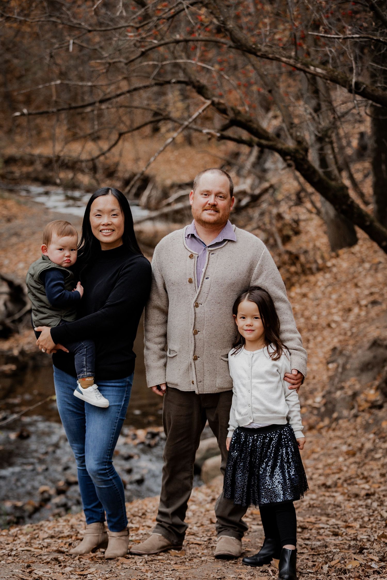Family enjoying autumn day together on leaf-covered ground.