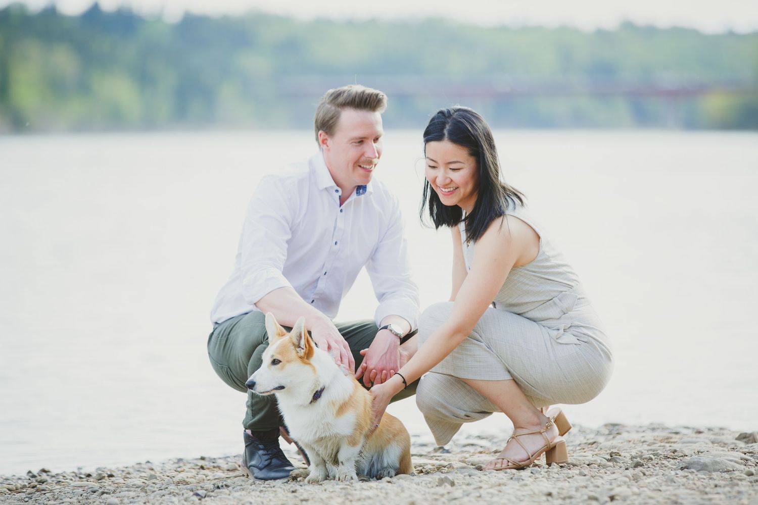 Couple poses with their corgi dog during lakeside engagement photoshoot.