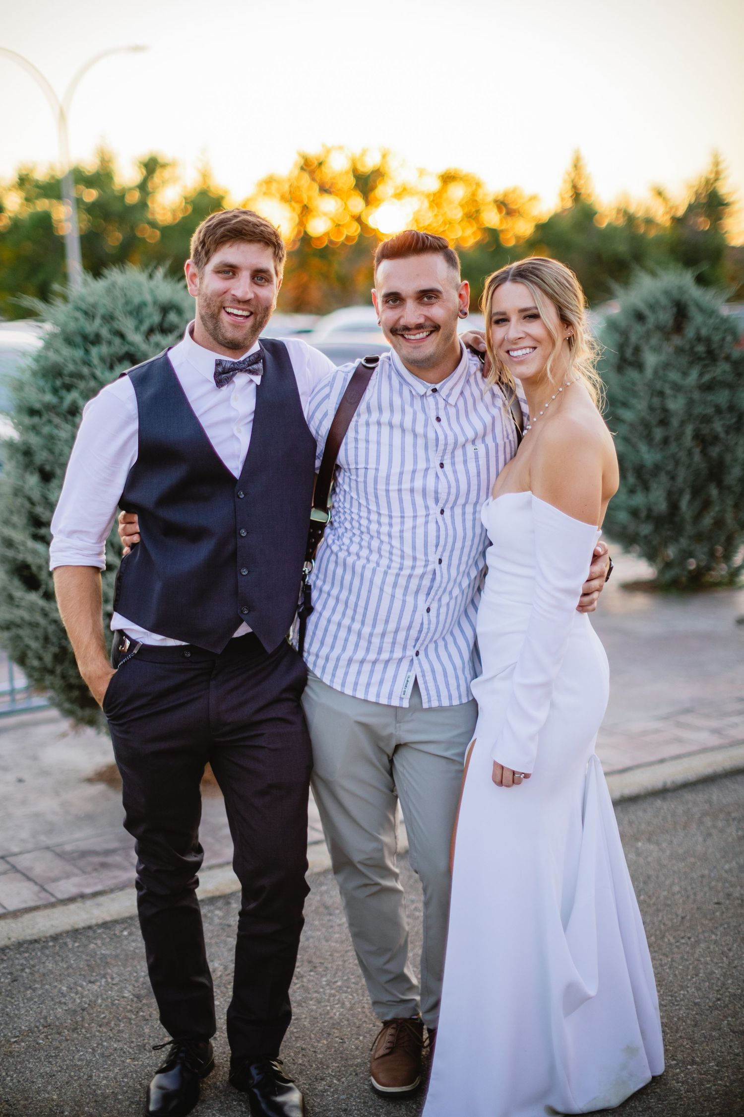 A wedding celebration photo with the couple and photographer in an outdoor setting at sunset.