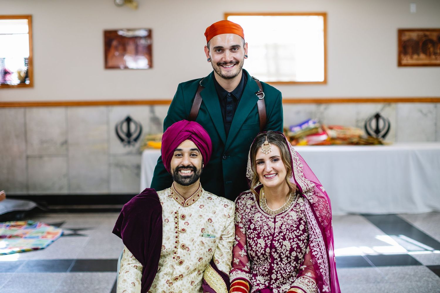 Wedding celebration scene with traditional attire and decorative indoor setting.