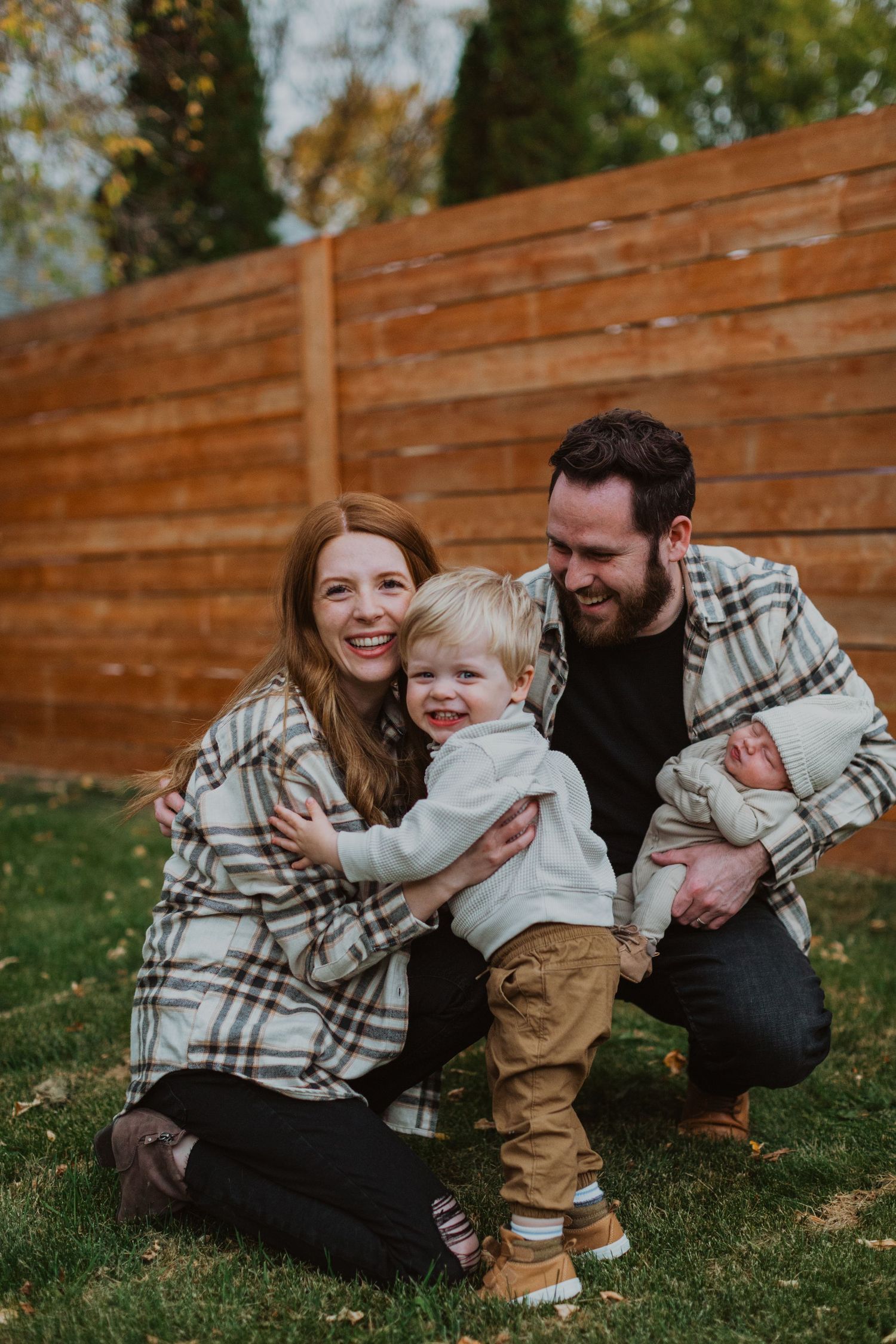 A family wearing matching plaid shirts shares a joyful moment together in their backyard.