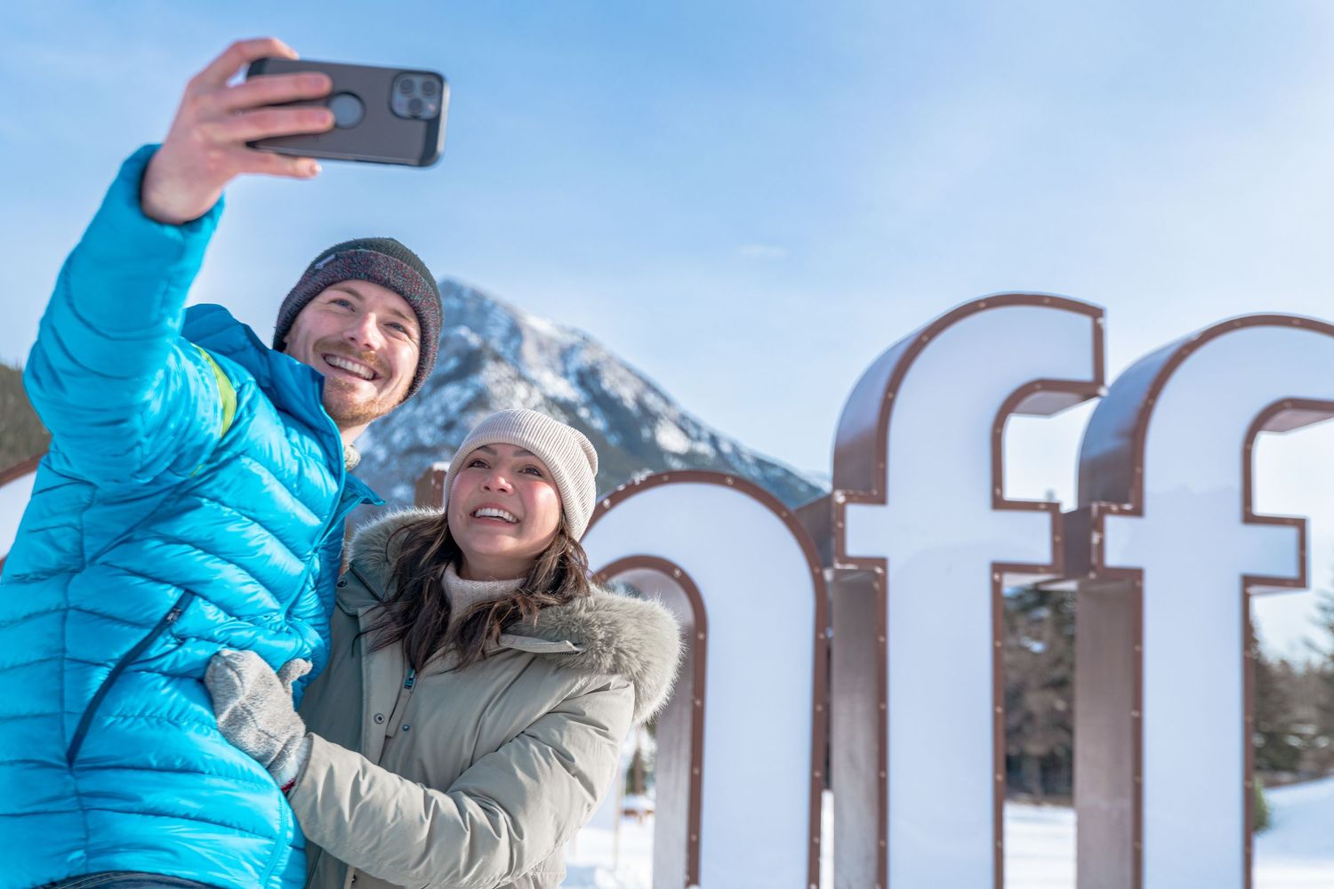 Two winter tourists are taking selfies in Banff National Park.
