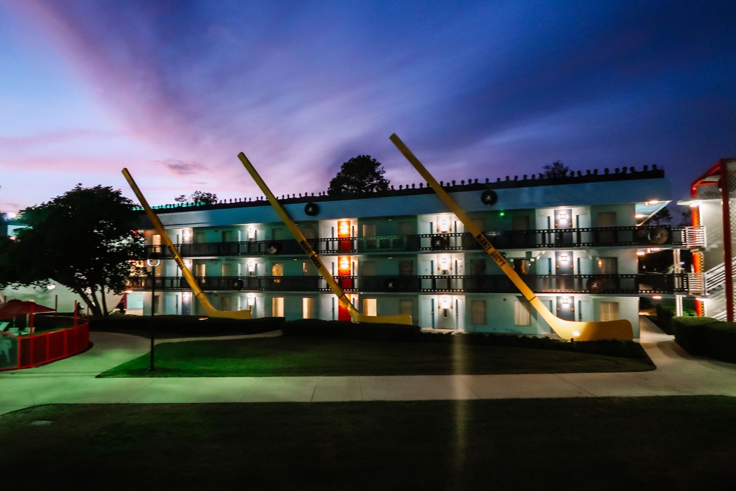 Multi-story motel building illuminated at dusk with dramatic purple and pink sky.