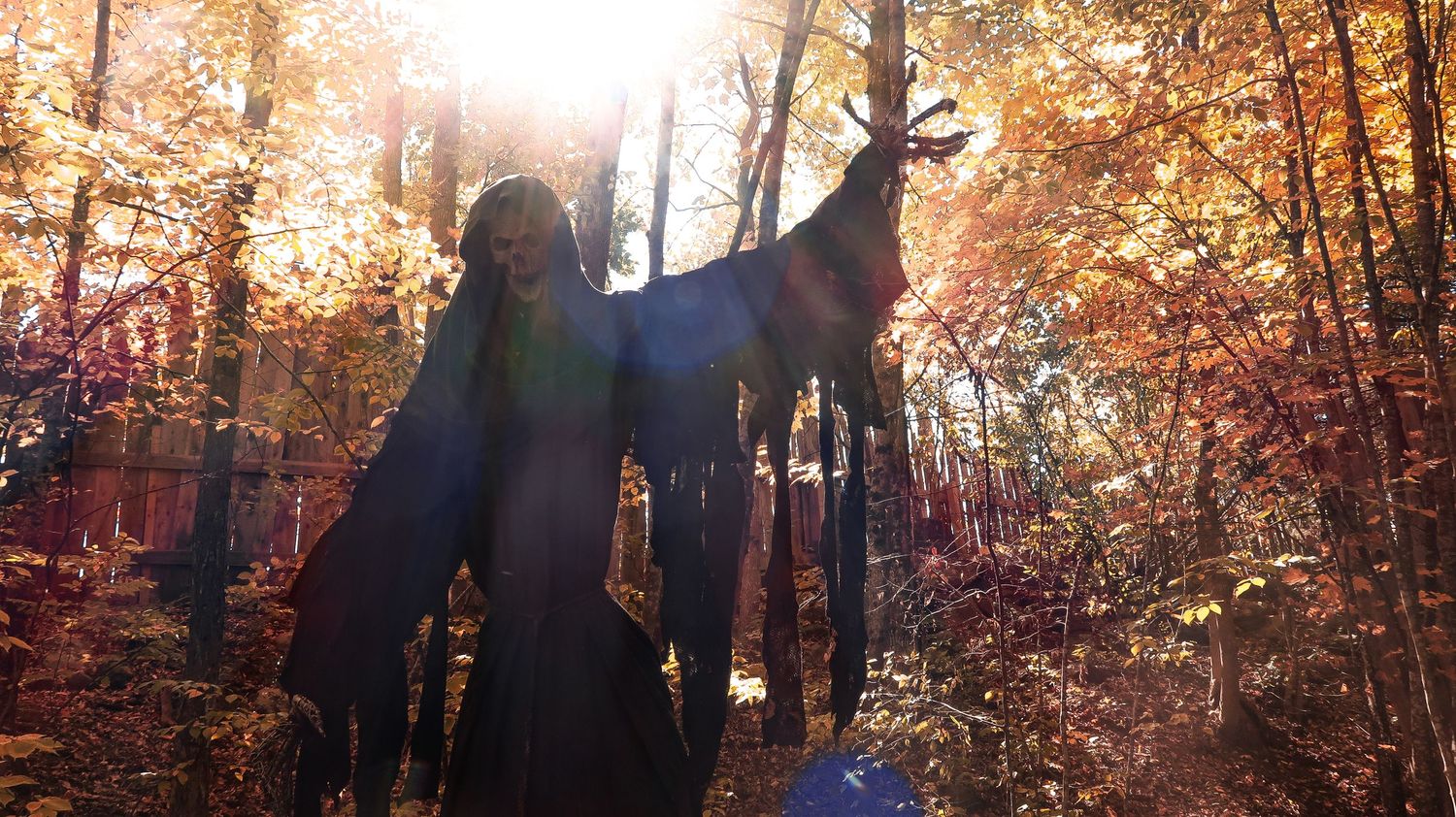 Spooky dark silhouette Halloween decoration of a monster figure among vibrant autumn forest trees.