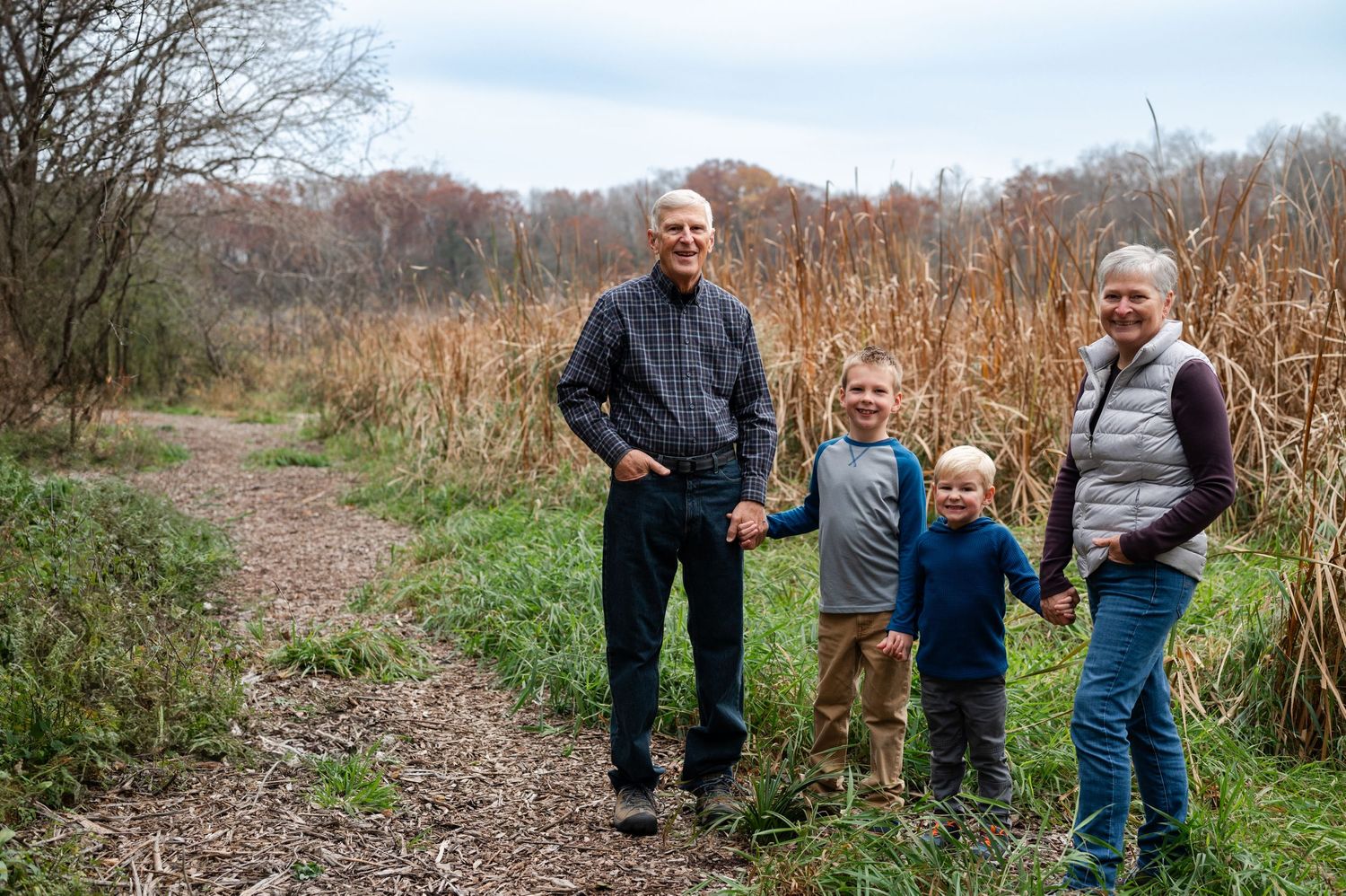 A group enjoying a nature walk together on a dirt trail surrounded by tall autumn grasses.