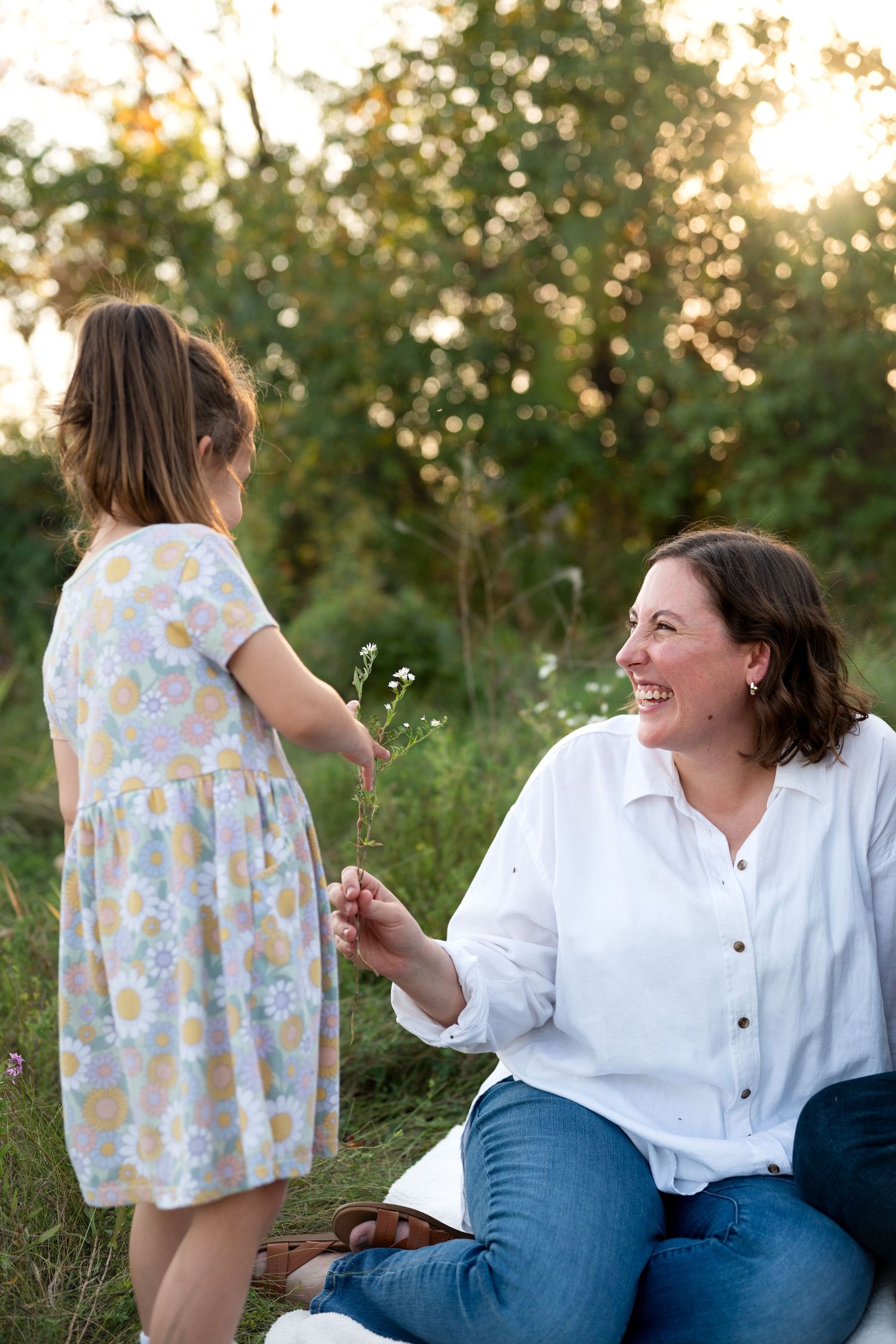 A joyful outdoor moment between two people in a sunlit field during golden hour, sharing smiles and connection.