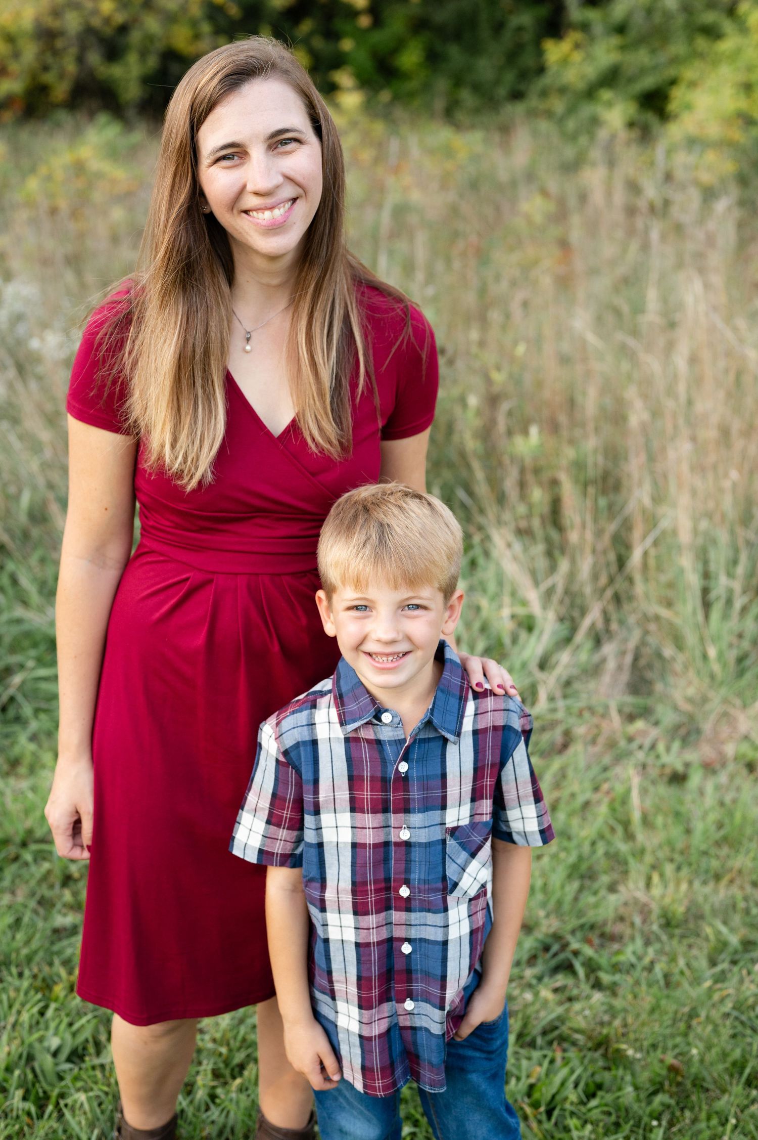 Portrait of two people standing together in front of natural grass field backdrop.