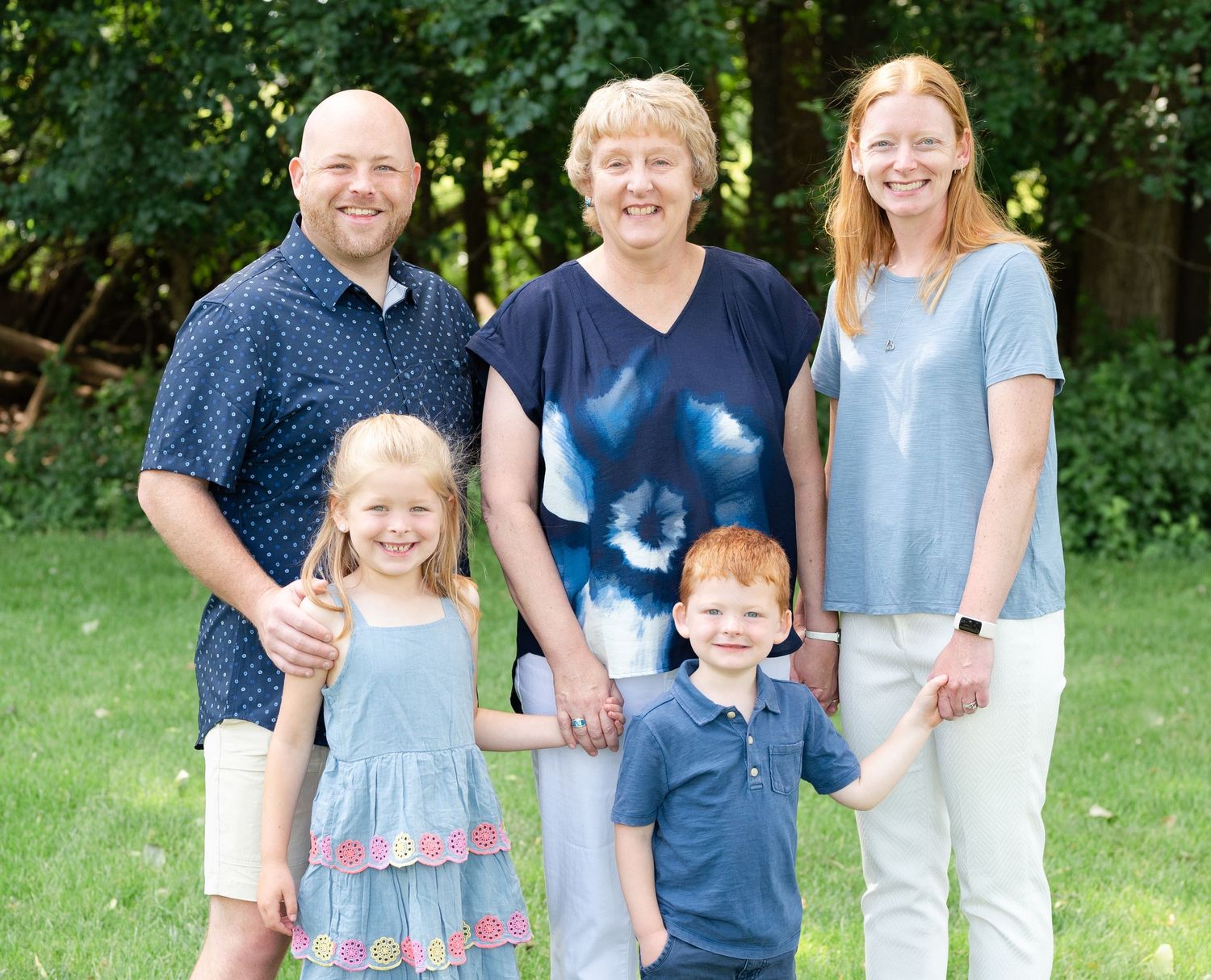 Family of five posing together in a garden setting on a bright summer day.