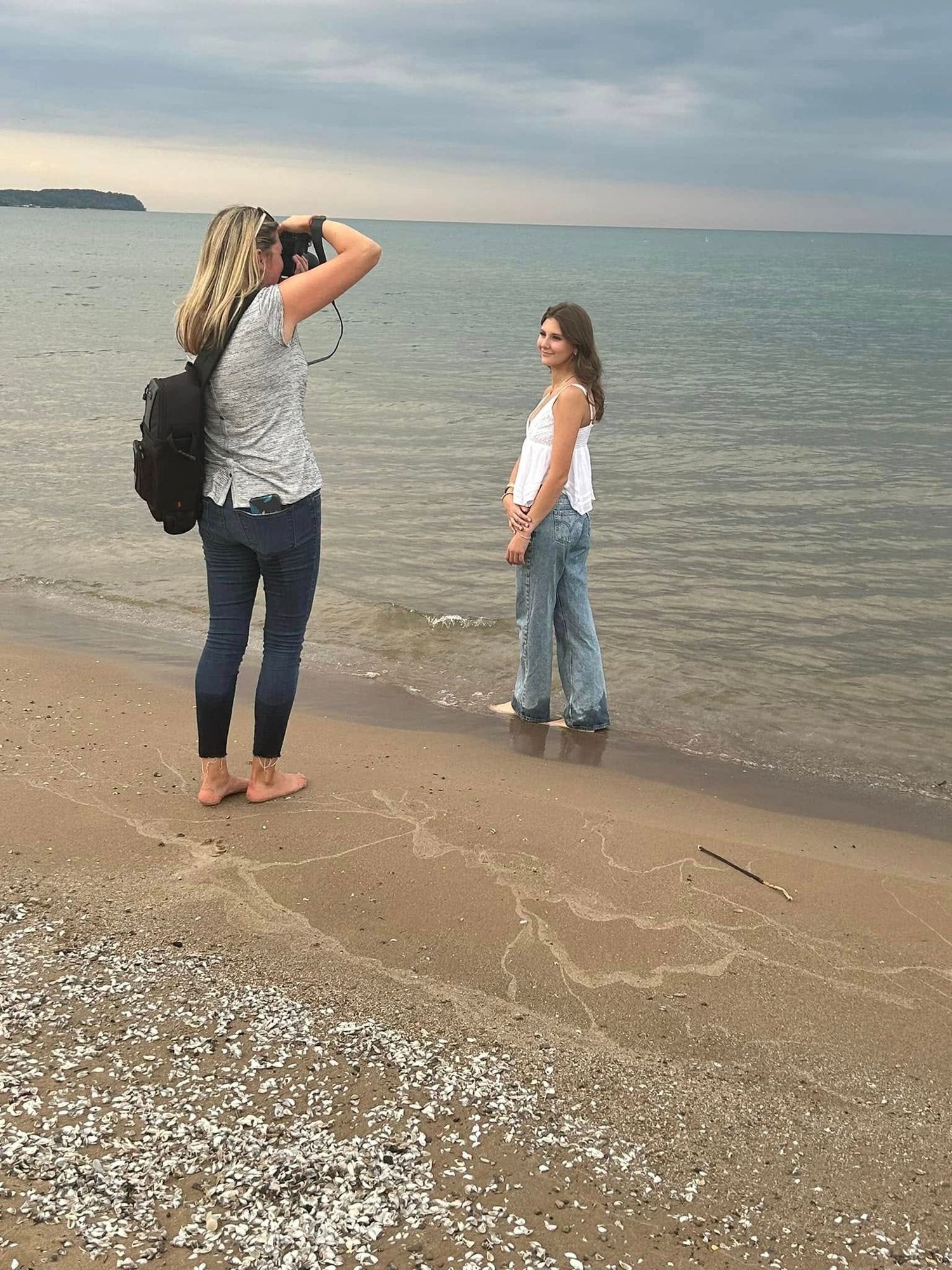 A photographer taking pictures of a model on a beach at sunset.