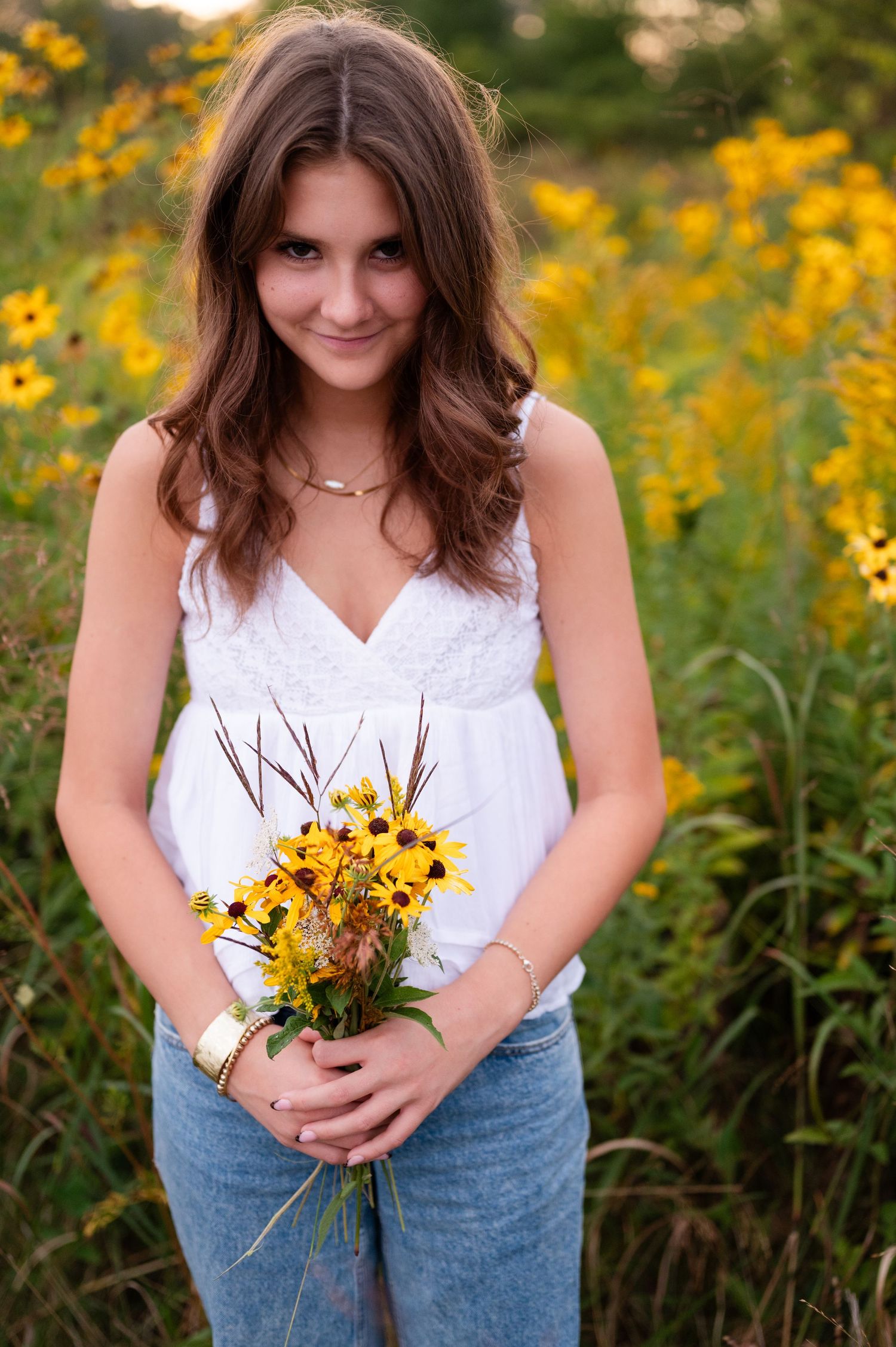 Portrait holding yellow wildflowers while standing in summer meadow.