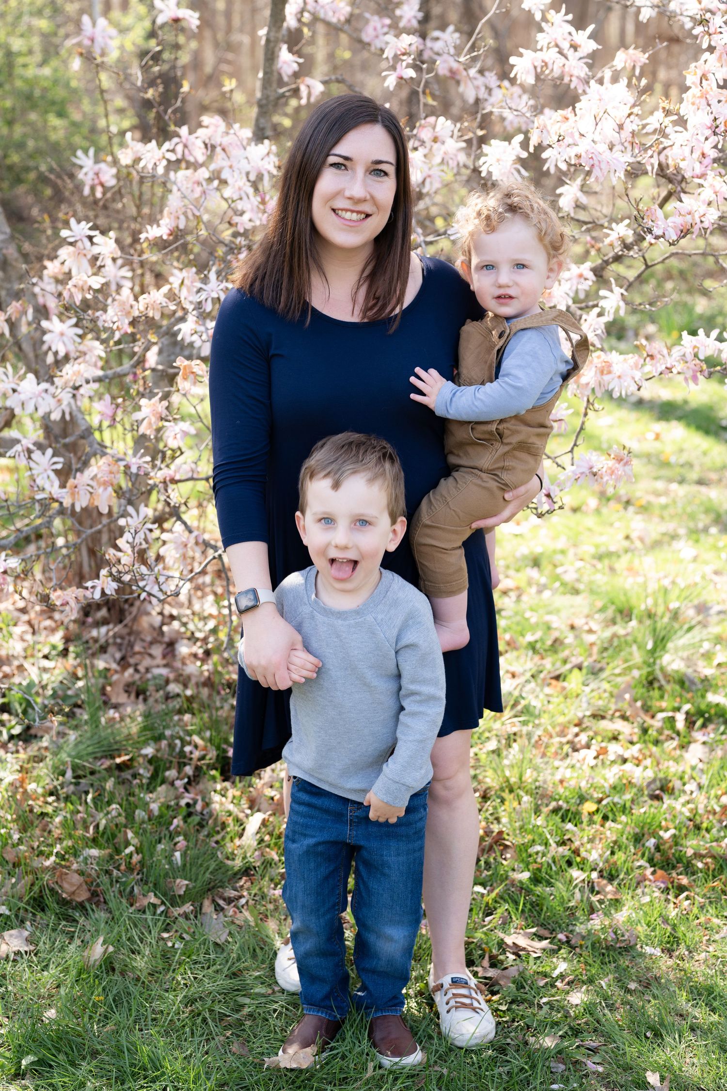 Sweet outdoor family photoshoot with blooming cherry blossoms in the background on a sunny spring day.