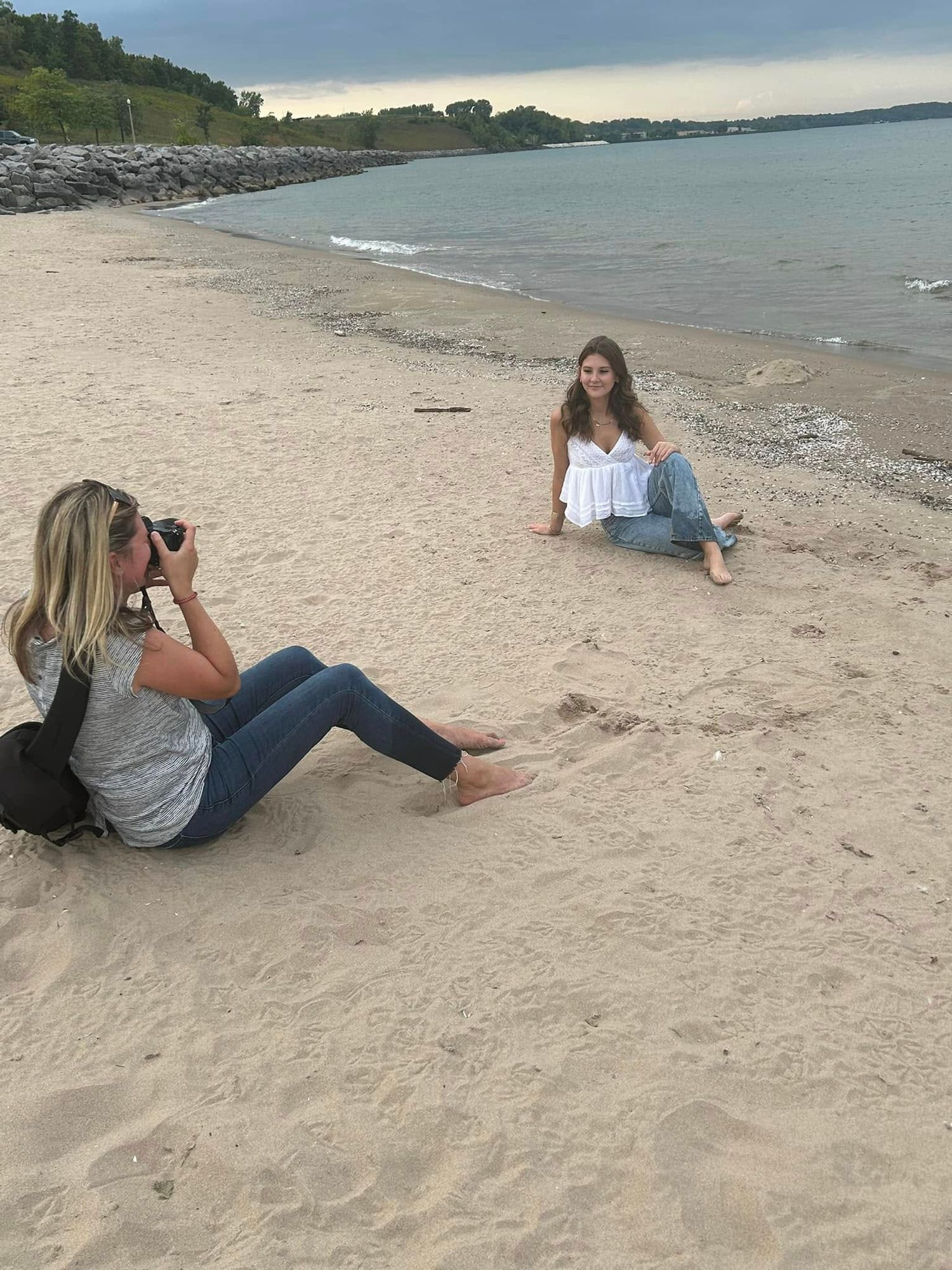 Behind the scenes photo shoot on a sandy beach with cloudy skies.