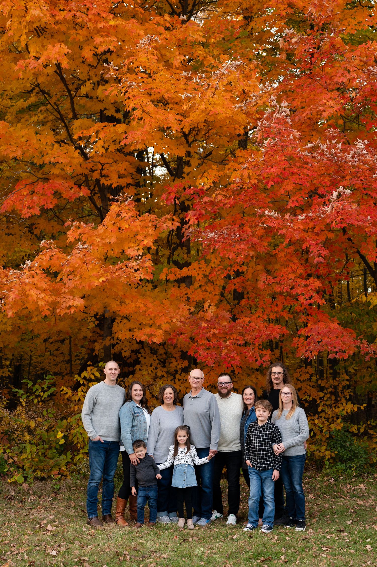 A group photo captured against vibrant orange and red autumn foliage in a wooded setting.