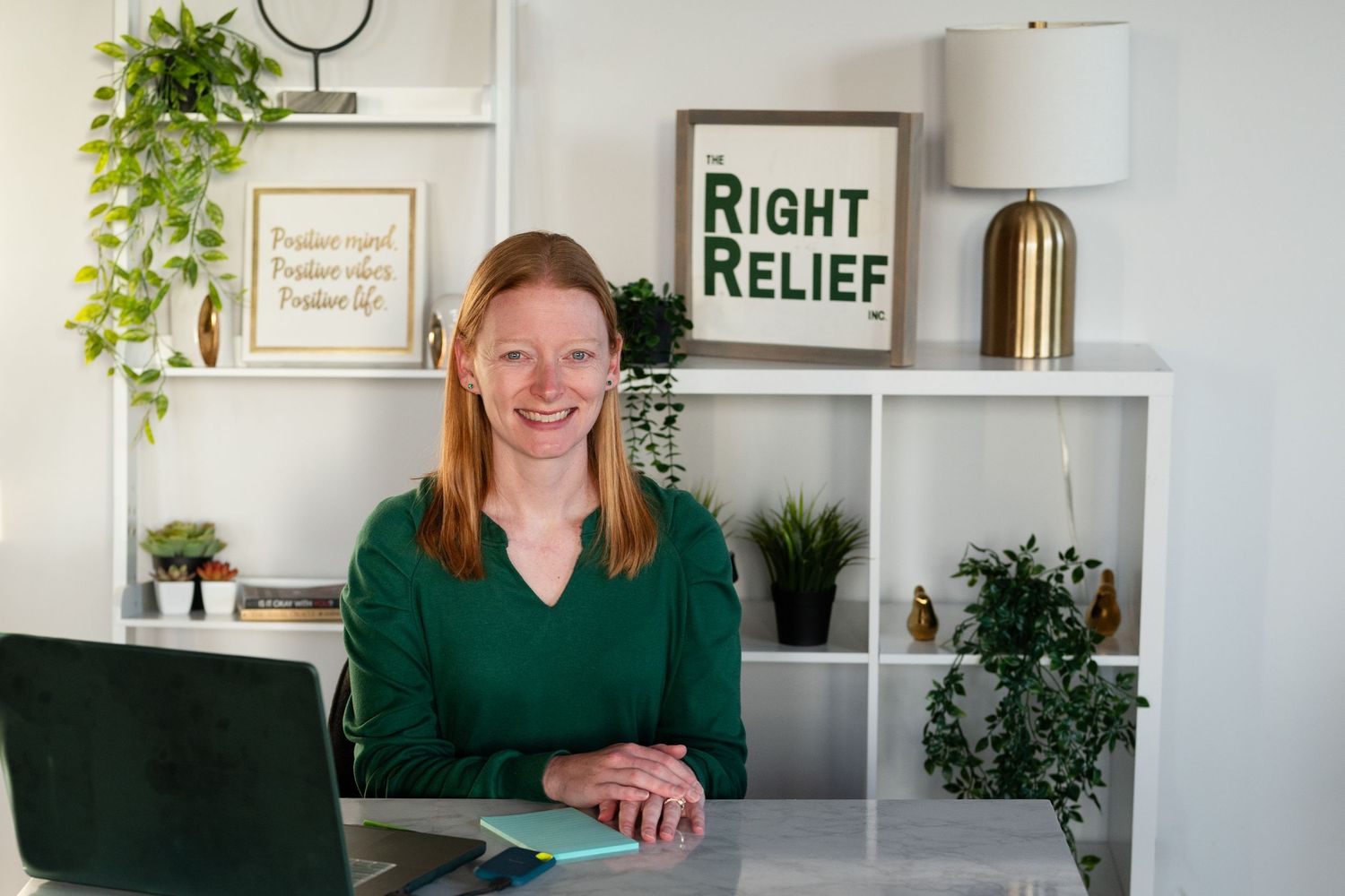 Person at desk with Right Relief branding and plants on white shelving in background.
