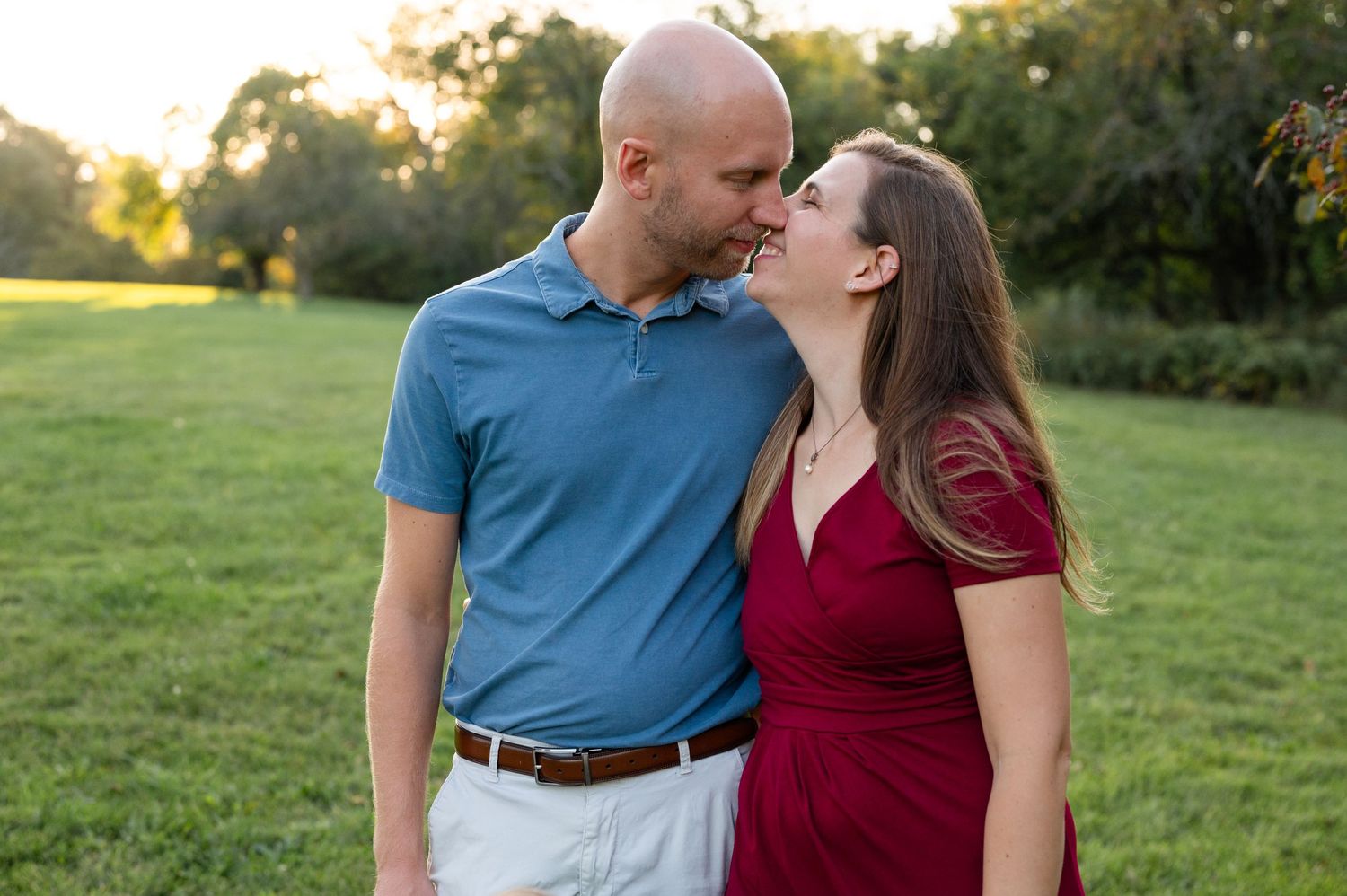 A romantic couple sharing an intimate moment in a park during golden hour.
