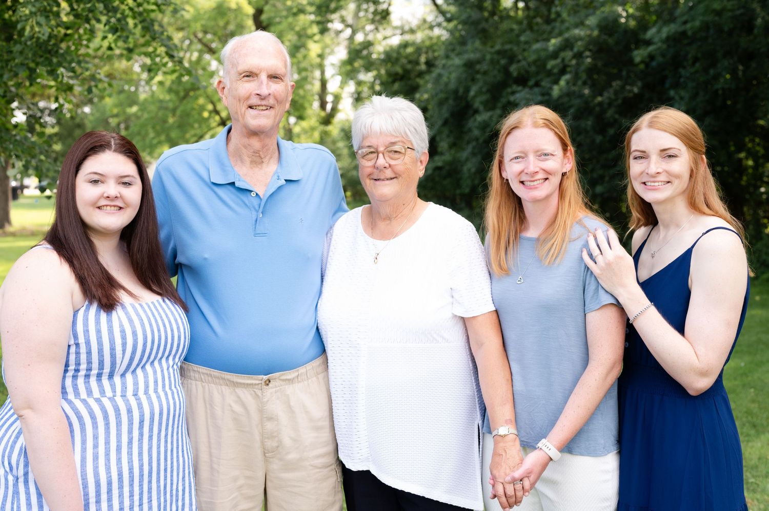 Family gathering outdoors with multiple generations wearing coordinated blue and white outfits.