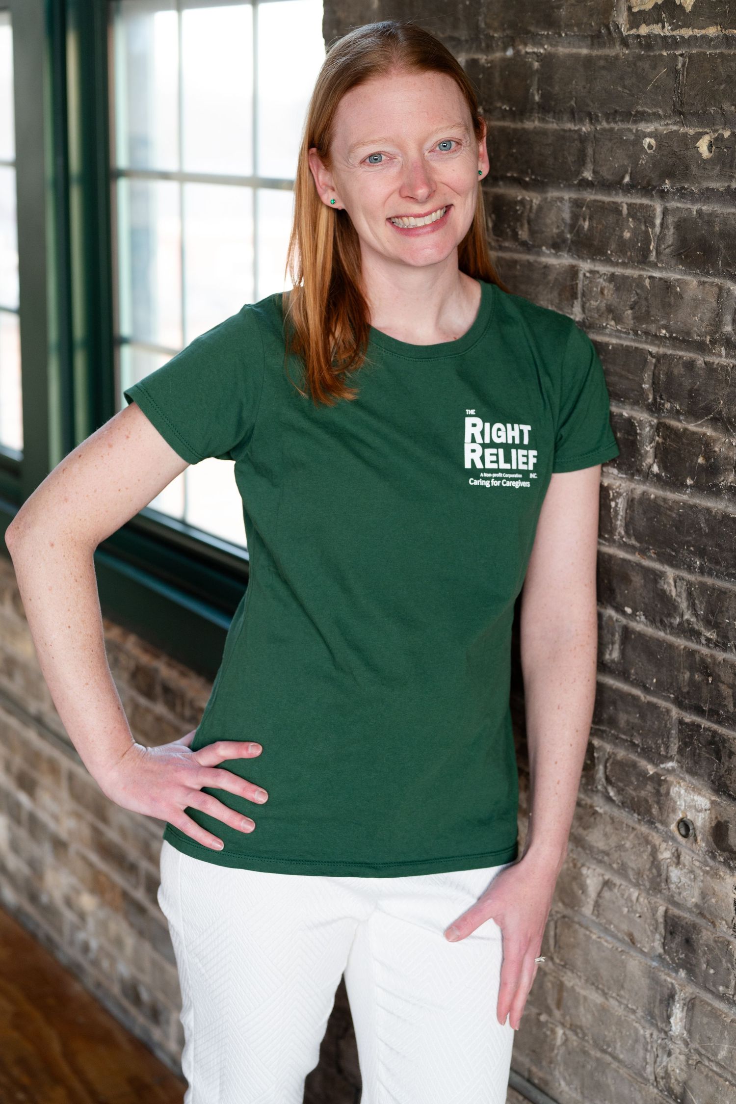 Person in green Right Relief t-shirt poses against brick wall interior.