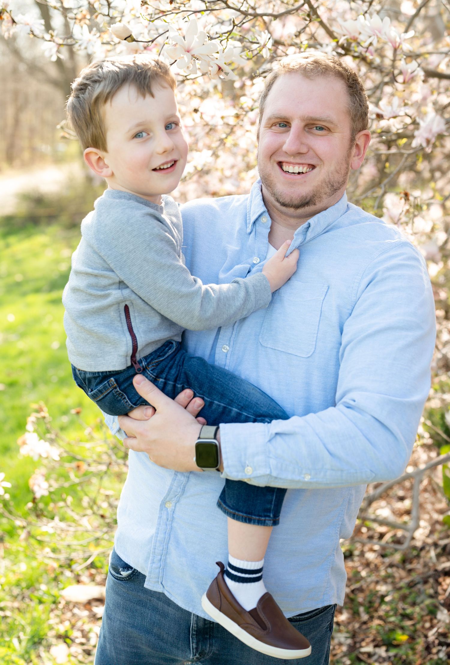 Happy springtime portrait beneath flowering cherry tree branches.