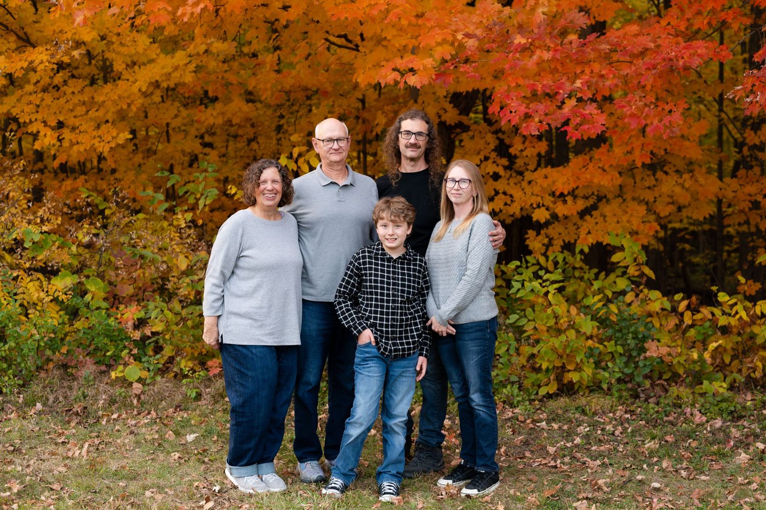Small group portrait with bright orange fall foliage in the background.