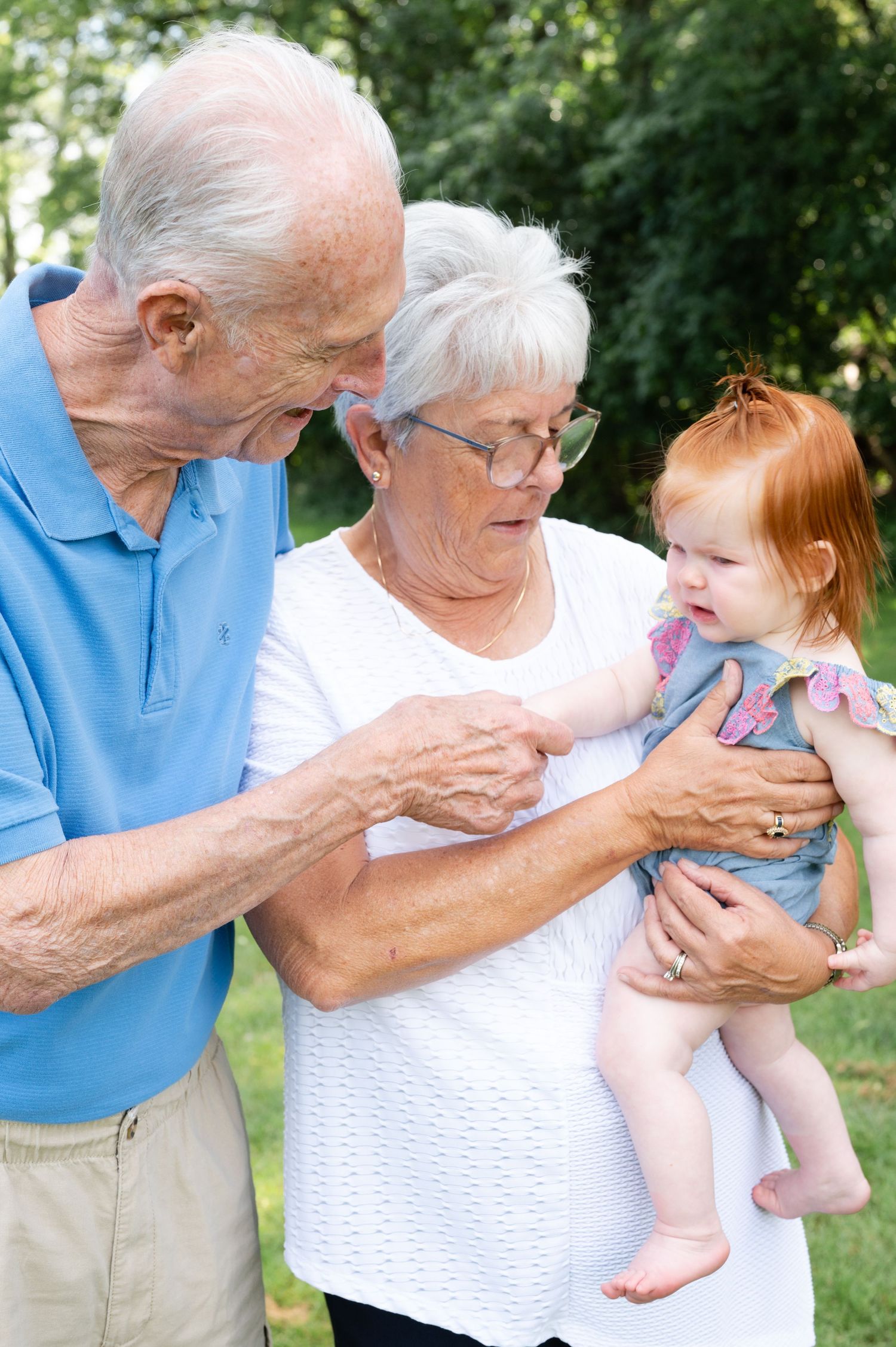 Three generations share a tender moment while playing with a baby outdoors.
