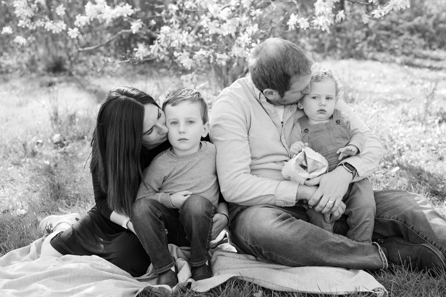 Black and white family portrait taken outdoors with soft natural lighting.