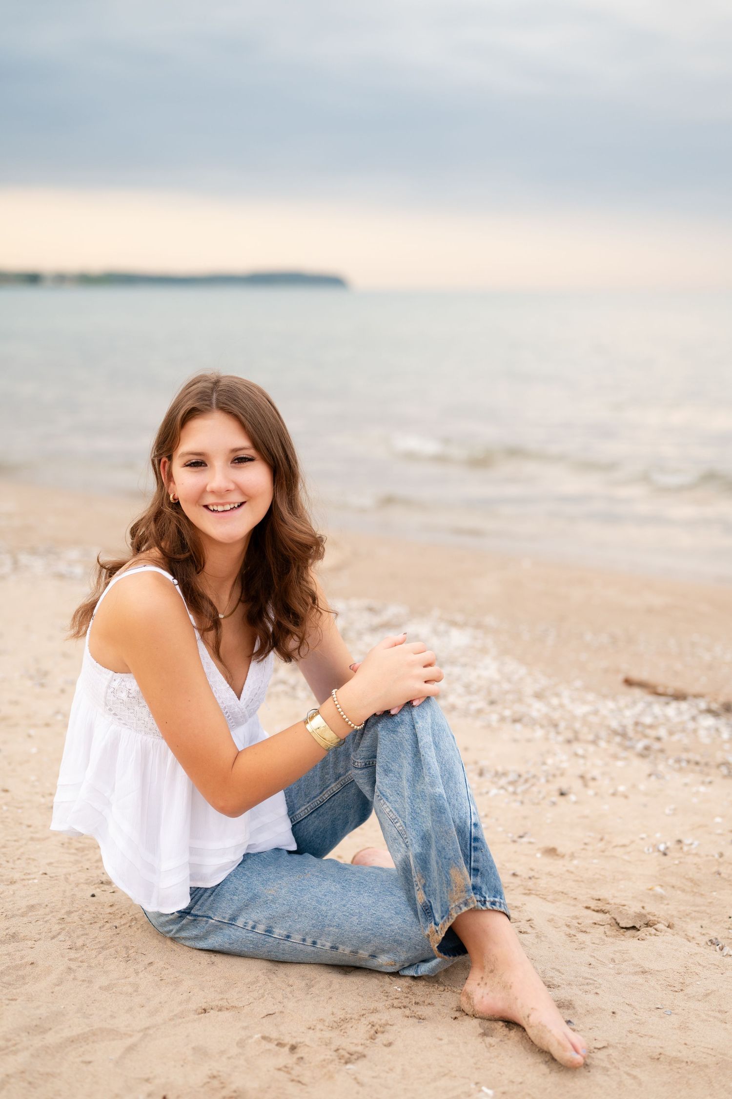 A casual beach portrait showing a relaxed pose on sandy shoreline at sunset.