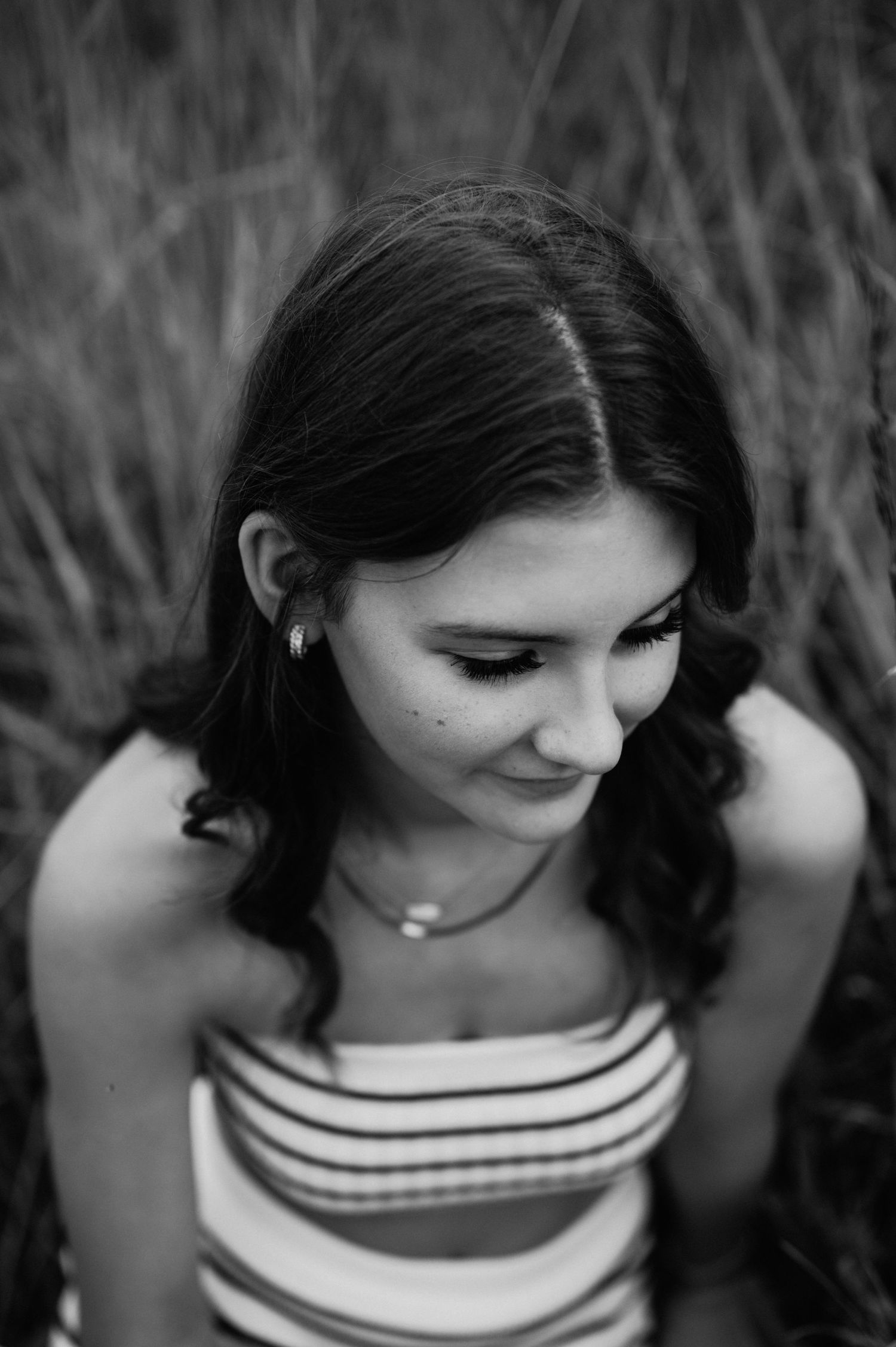 Black and white portrait in tall grass wearing striped top.