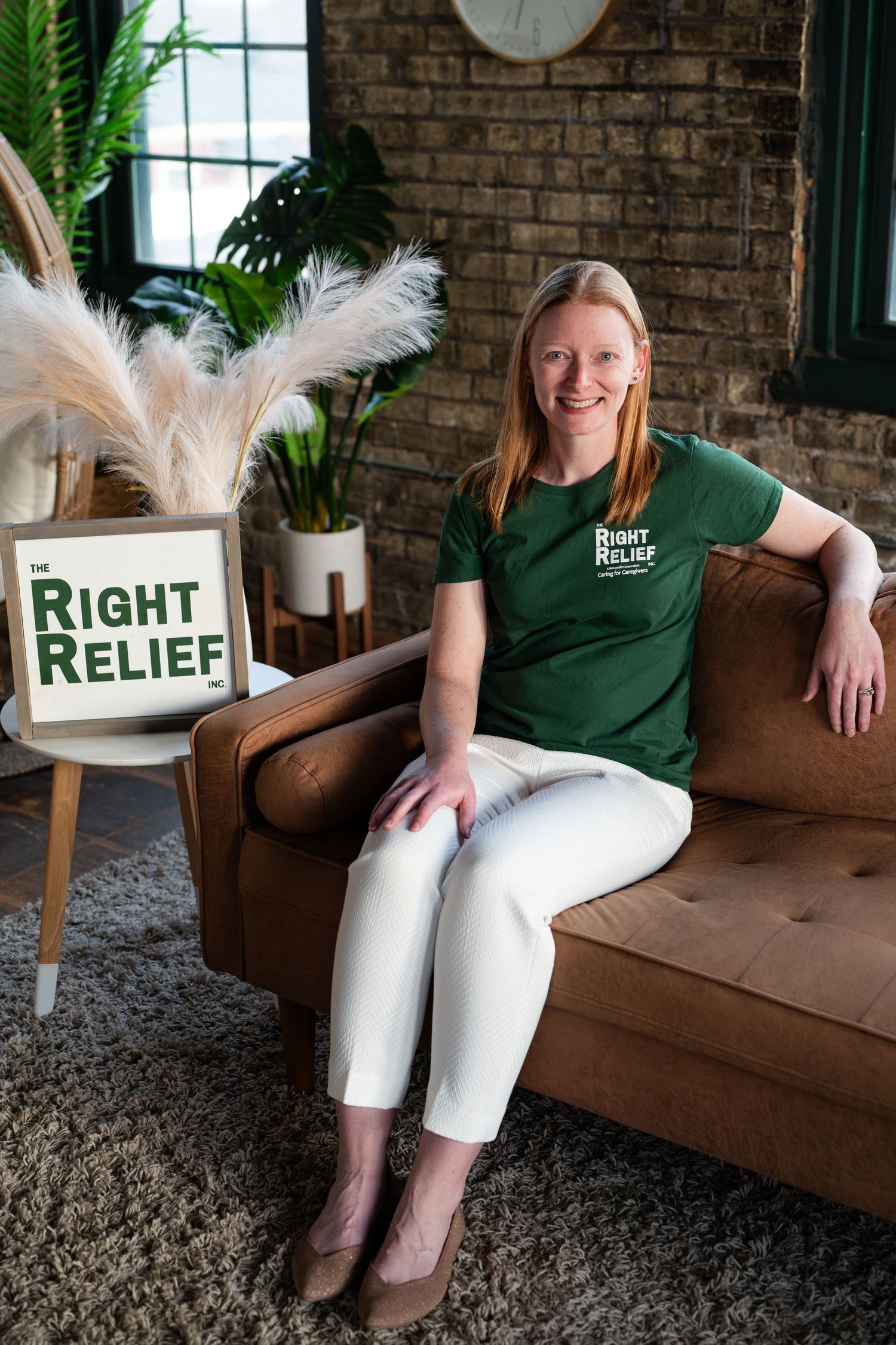 Person in green shirt sits on brown couch with Right Relief branding and plants in modern office setting.
