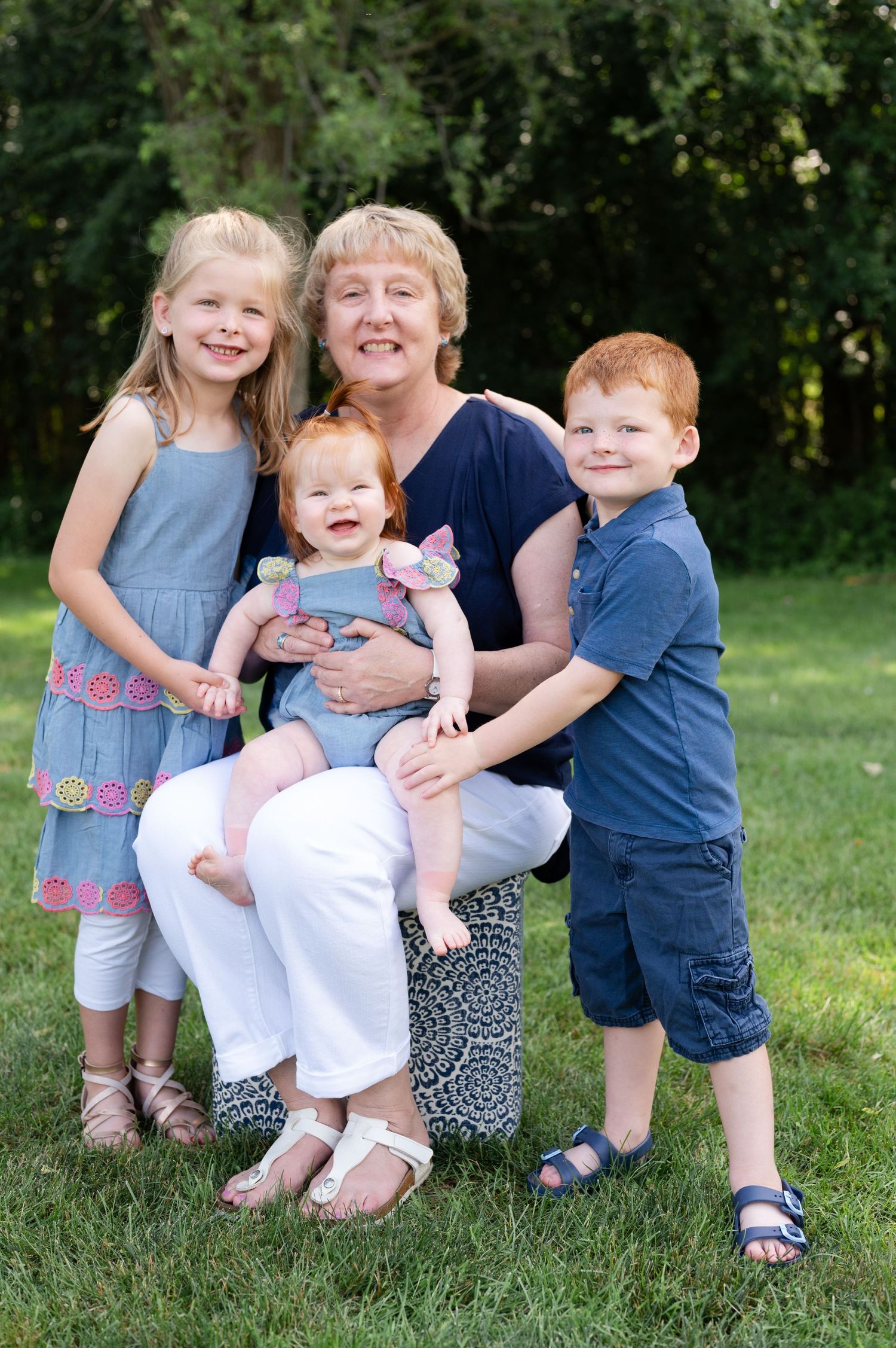 Multi-generational outdoor family portrait on grass with children in summer attire.