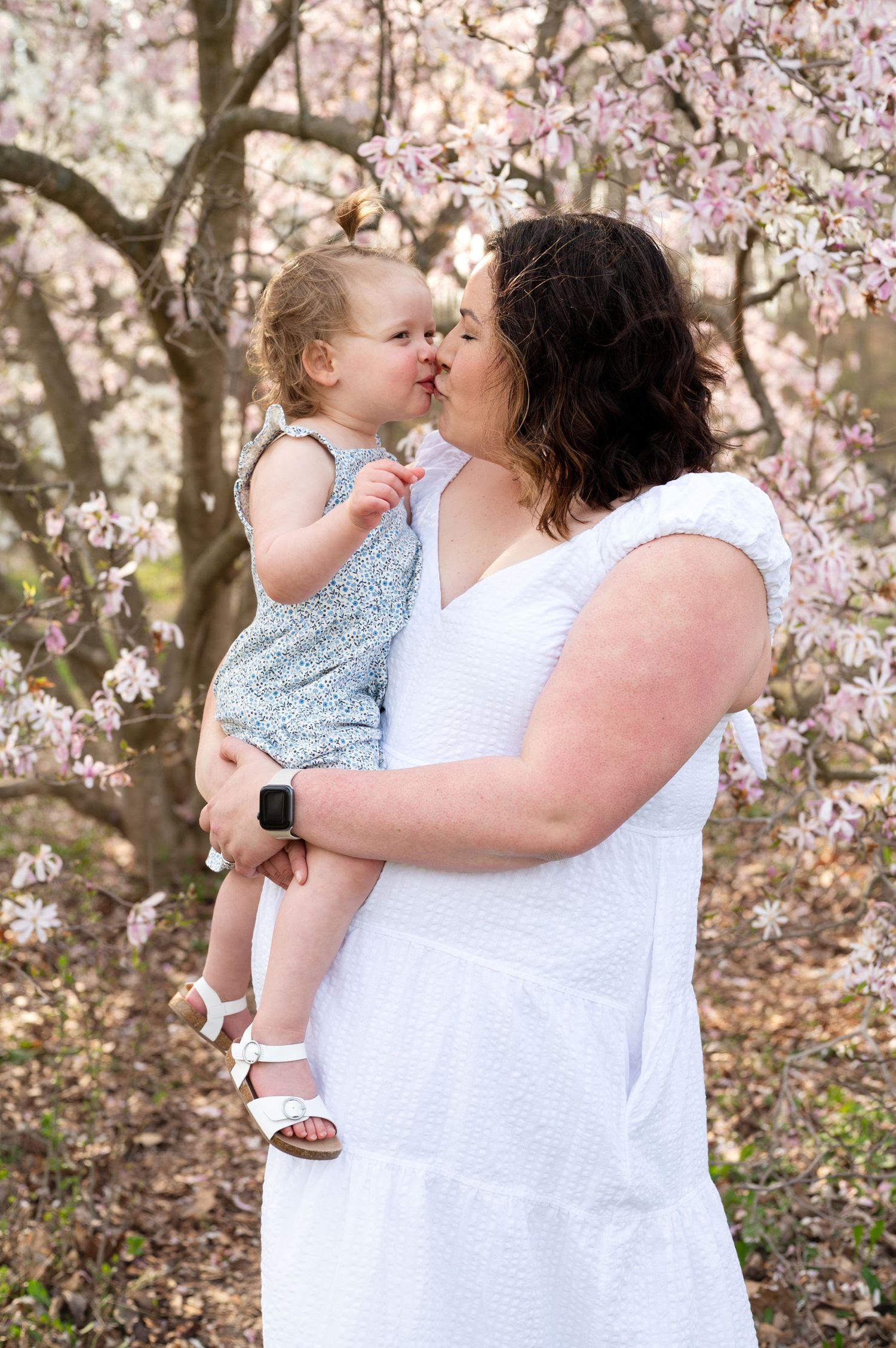 A tender moment shared under blooming cherry blossom trees on a spring day.