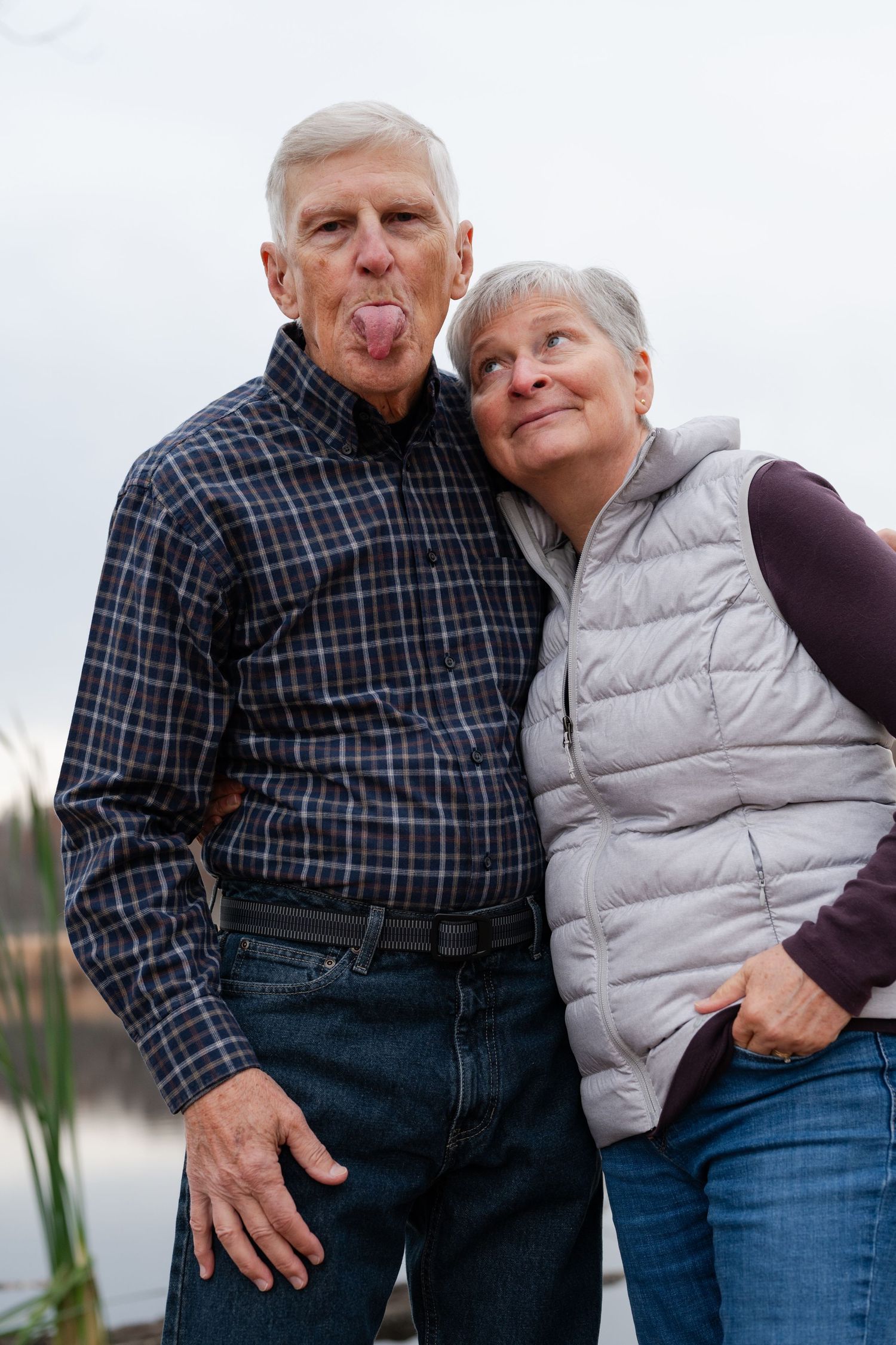 Playful couple sharing intimate moment by waterfront with natural scenery.