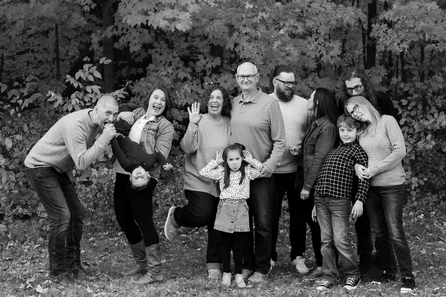 Black and white candid group photo with playful poses against a forest backdrop.
