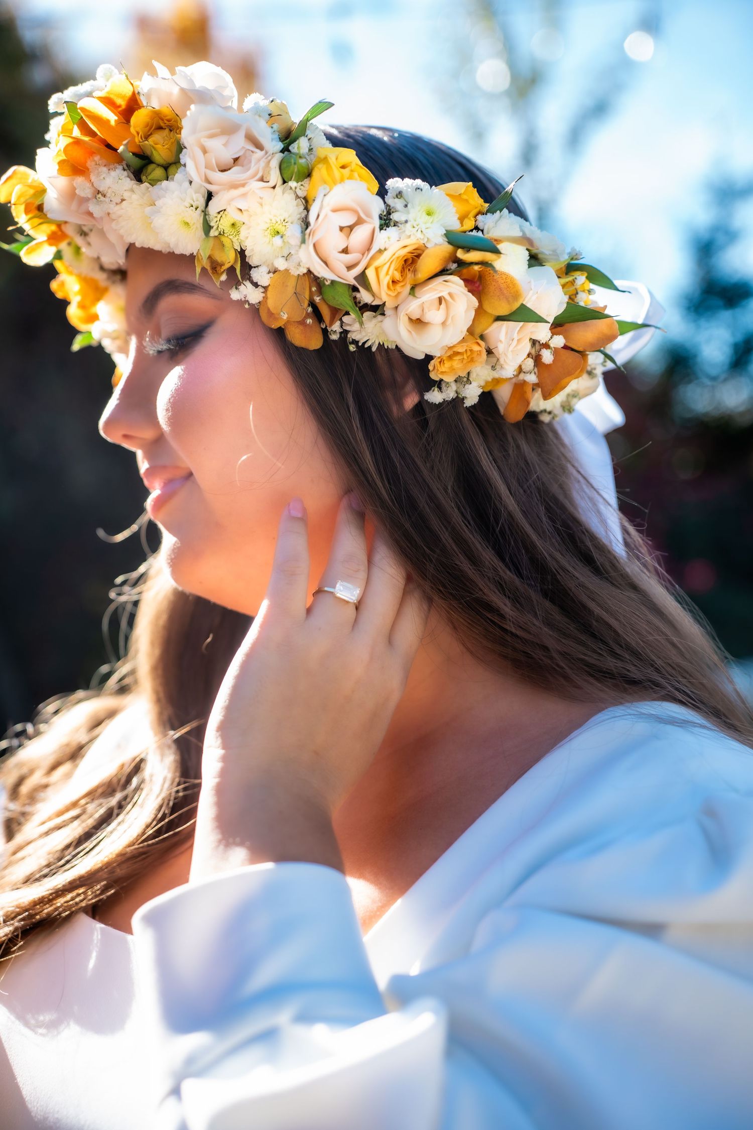 Person wearing a floral crown of yellow and orange flowers in soft sunlight.