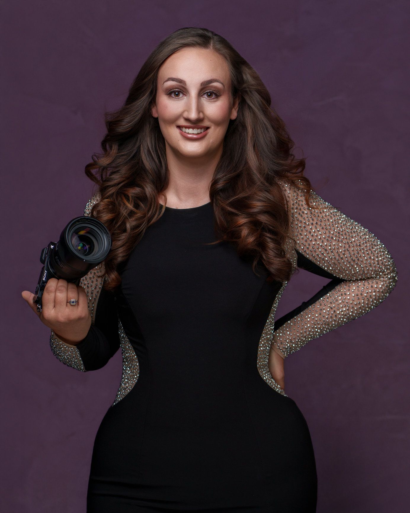 Studio photography portrait with person in black outfit against dark purple background.
