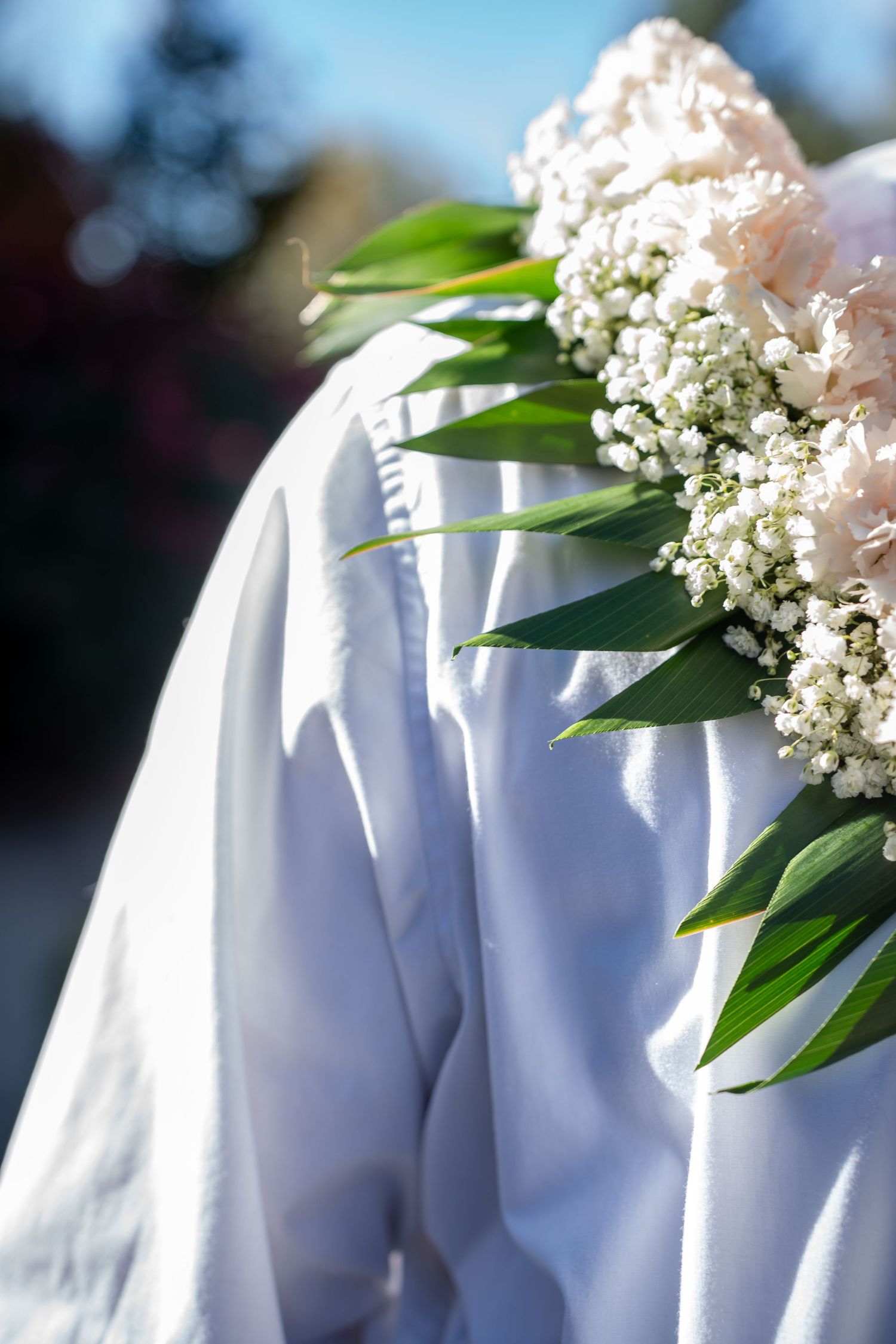 Detail shot of white fabric with delicate baby's breath flowers and green leaves.