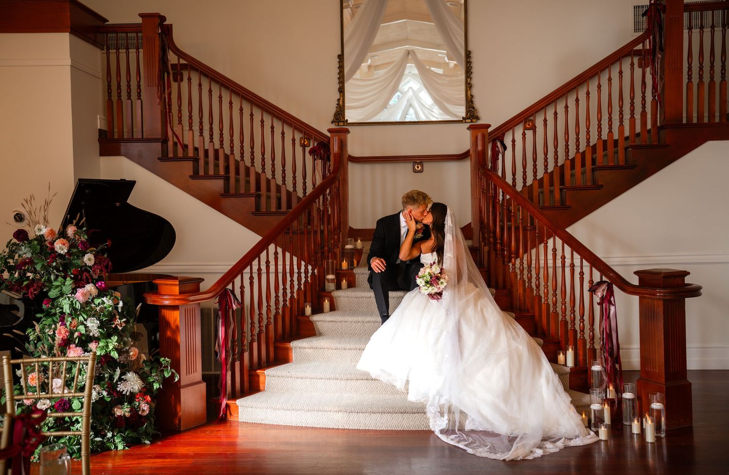 Panoramic view of elegant wooden staircase decorated with wedding floral arrangements.