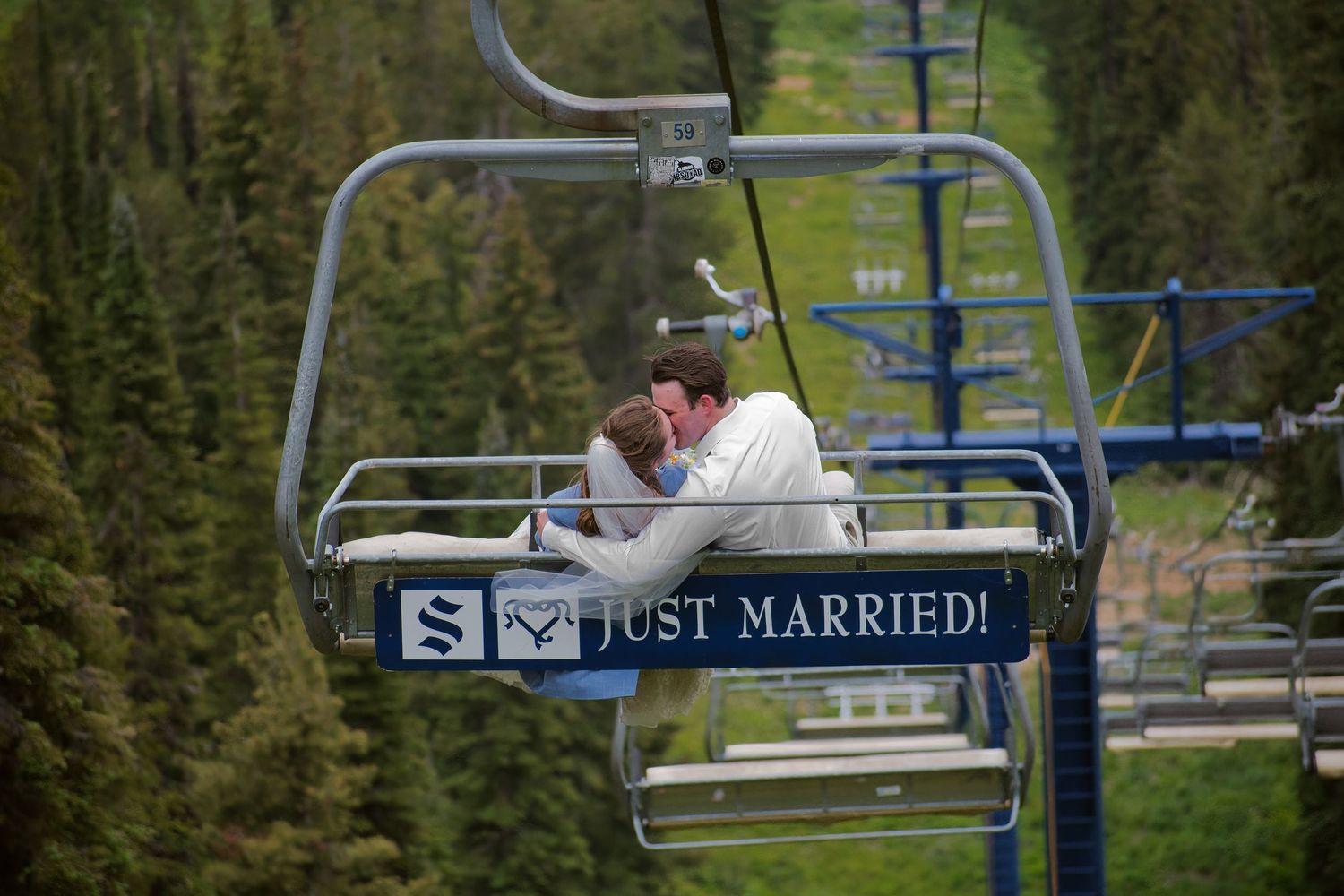 Bride and groom kiss as they ride ski lift in Sandpoint, Idaho