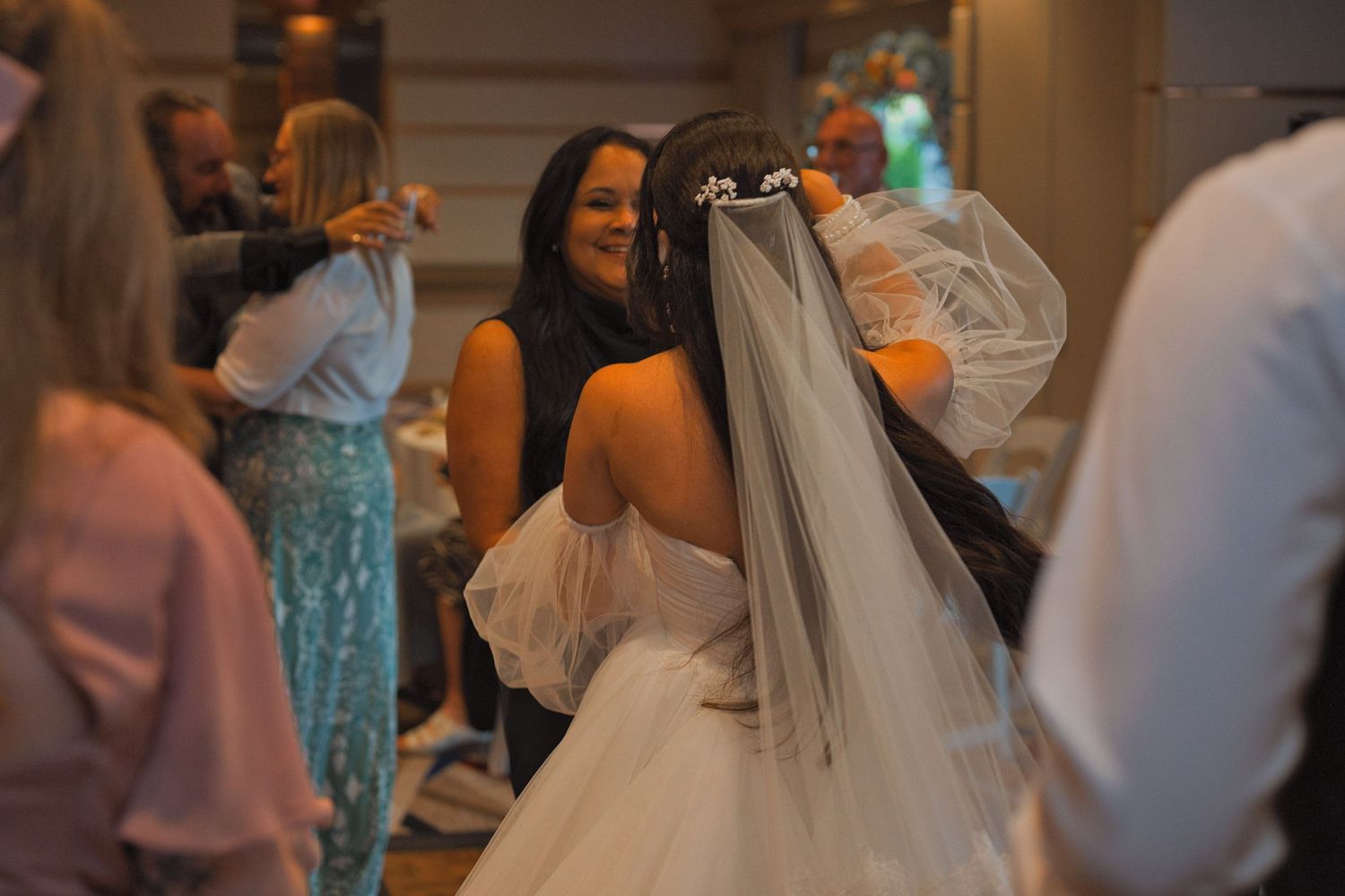 Picture of the back of the bride as she dances with he mother, the focus of the picture on the bride's veil.