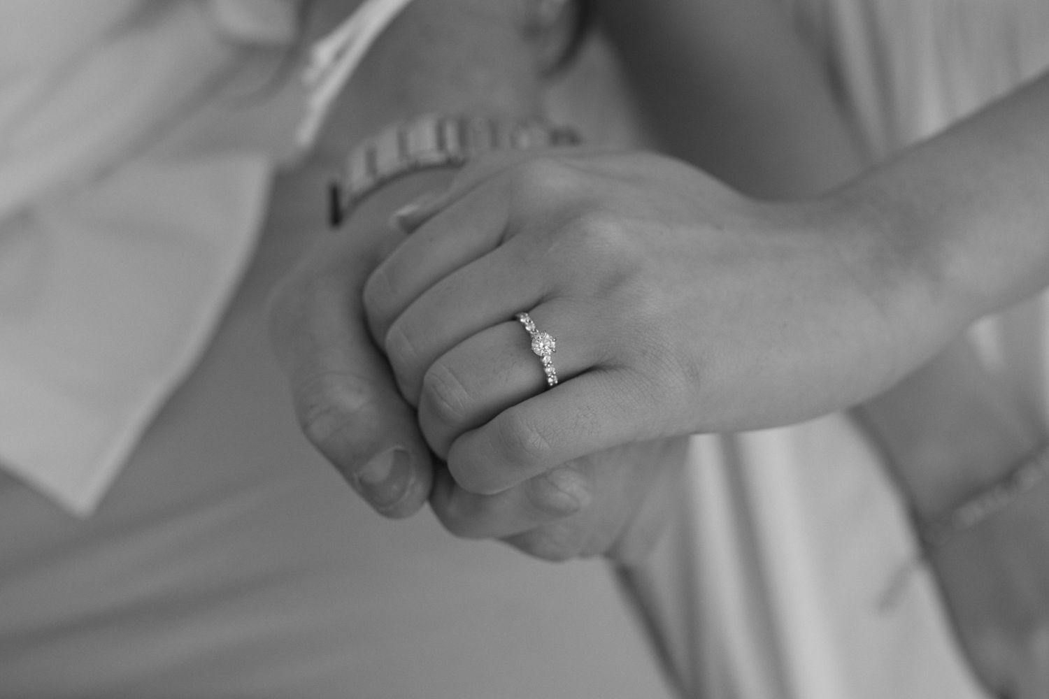 Engaged couple holds hand as engagement ring sparkles