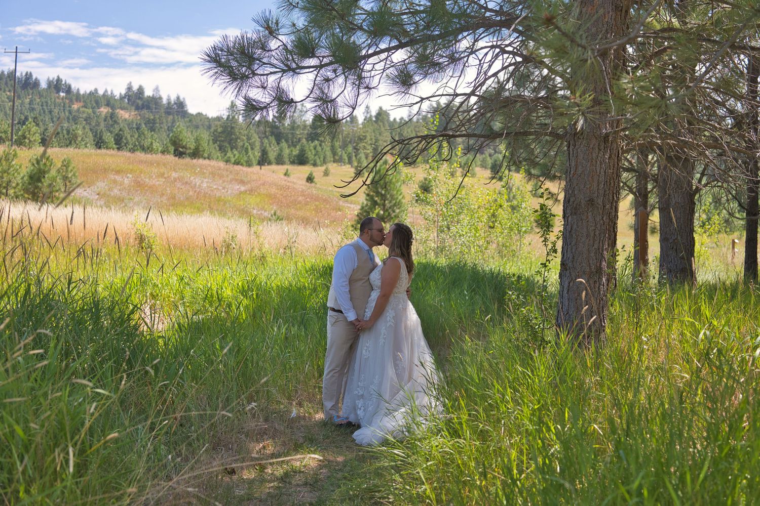 Bride and groom share quiet kiss beneath the trees before ceremony