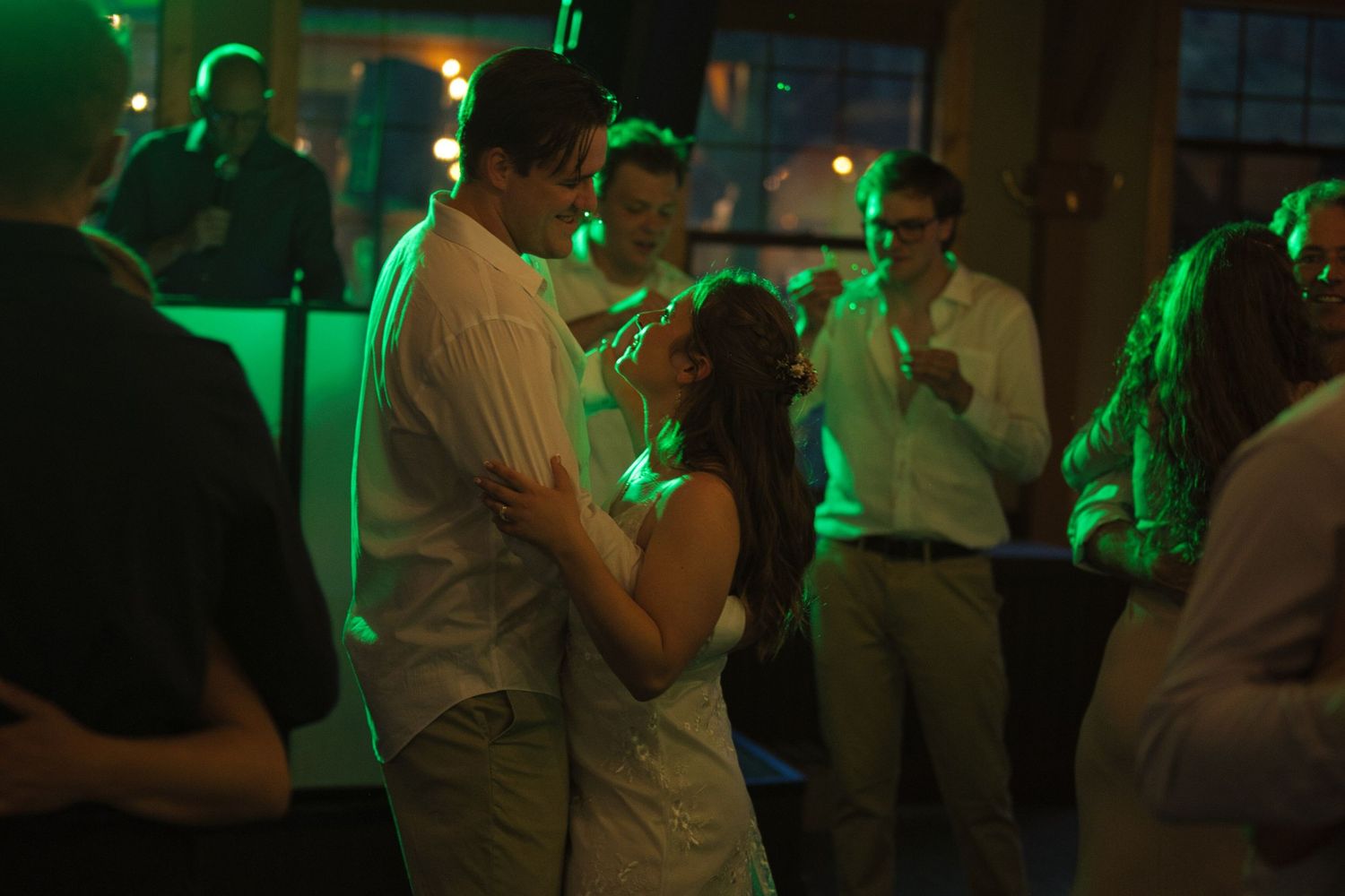 Colored lights from the dance floor shine on bride and groom