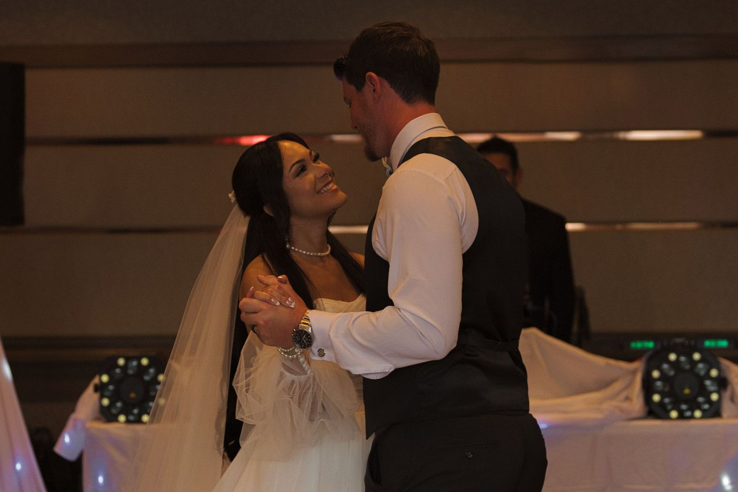 Bride smiles up at the groom while they hold hands during their first dance.