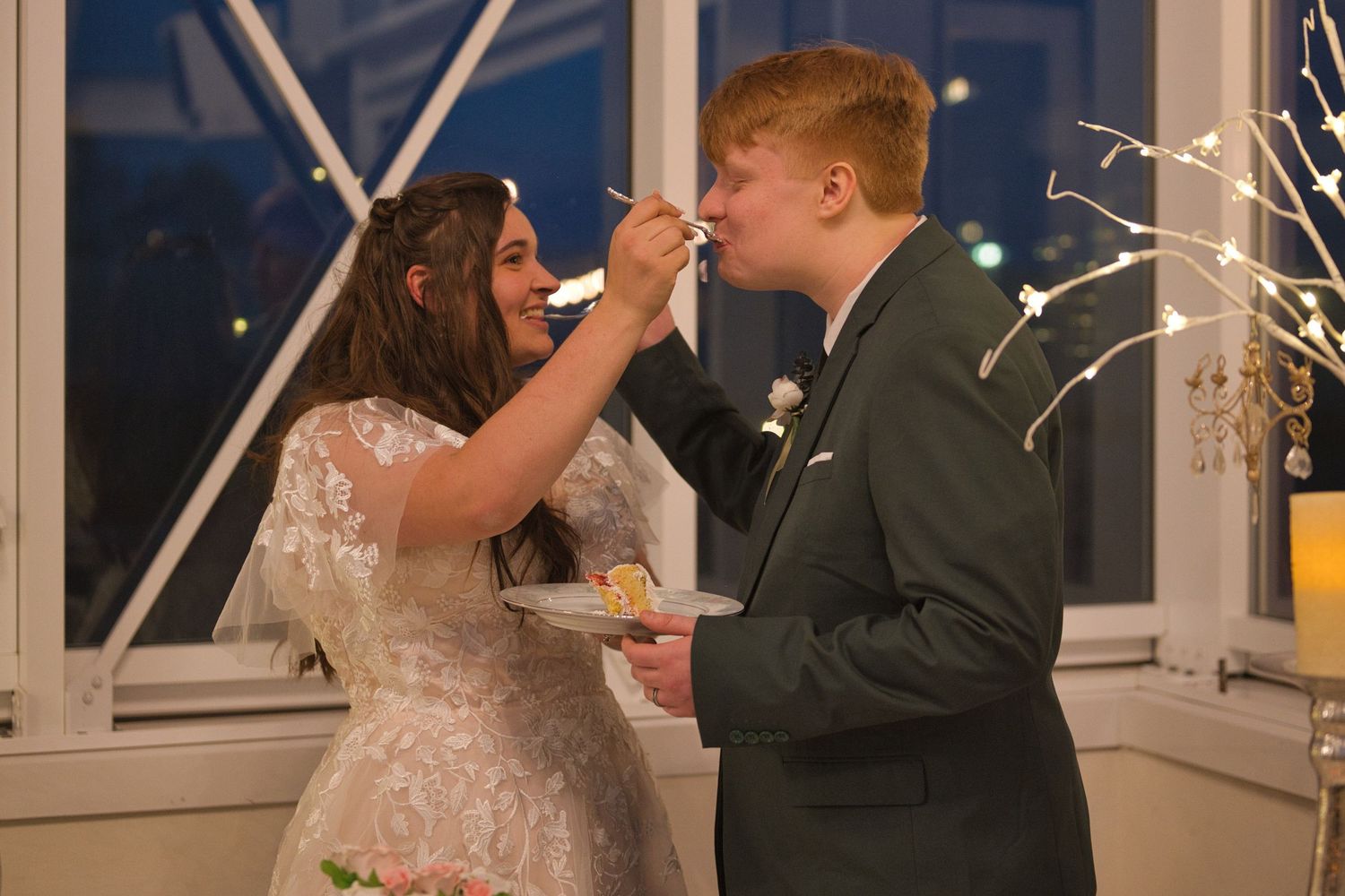Couple sharing a bite of cake during wedding reception