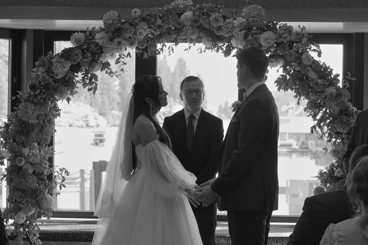 A black and white photograph featuring the bride, groom, and officiant standing during the wedding ceremony.
