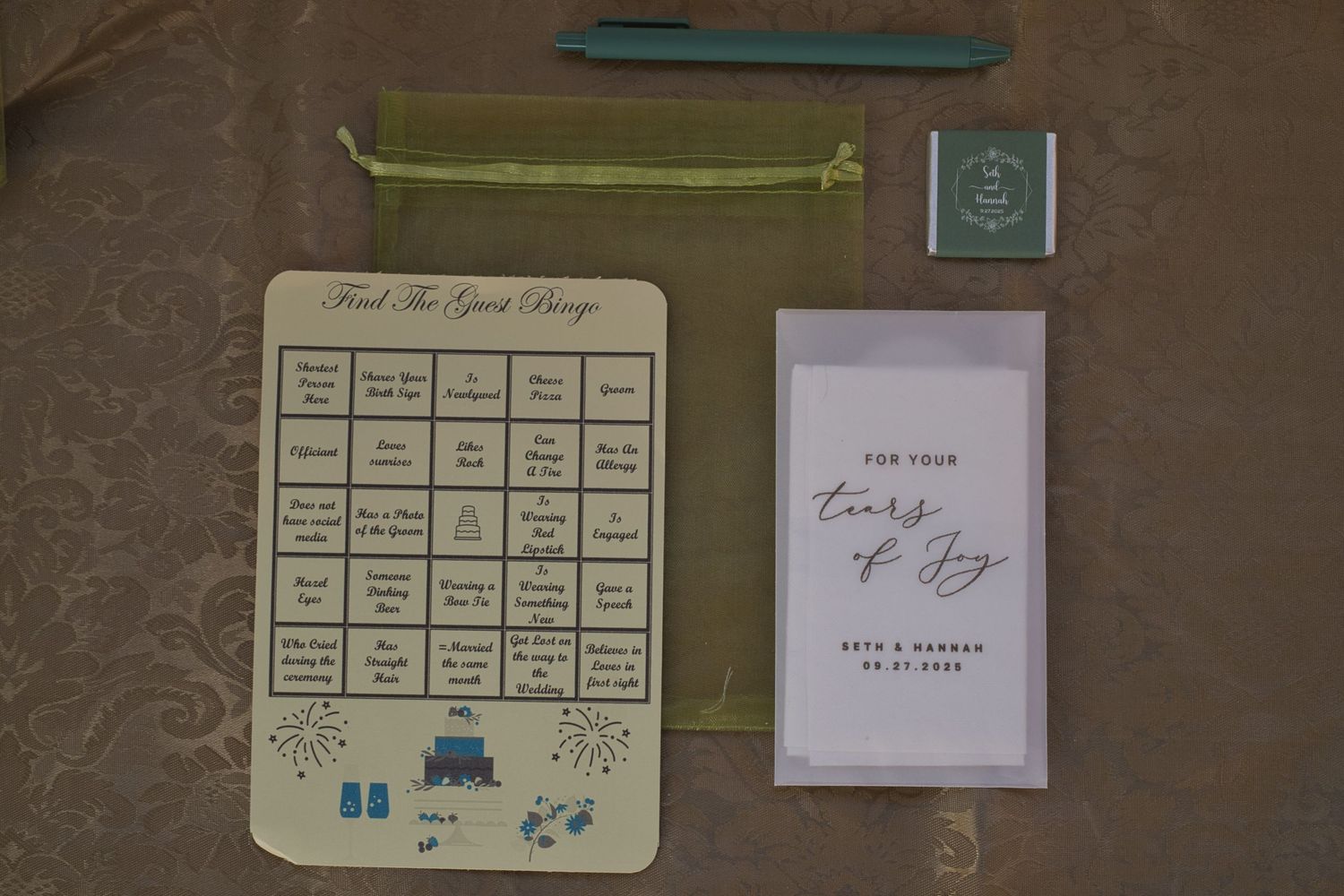 Flat lay of wedding guest gift that includes bingo sheet, tissues, pen, and chocolate.