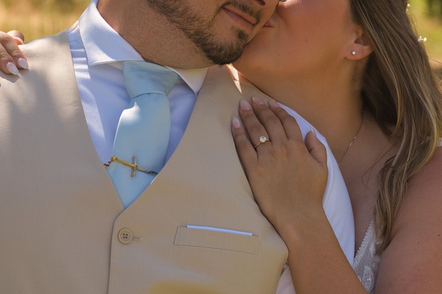 Bride kisses groom's cheek while taking couples portraits