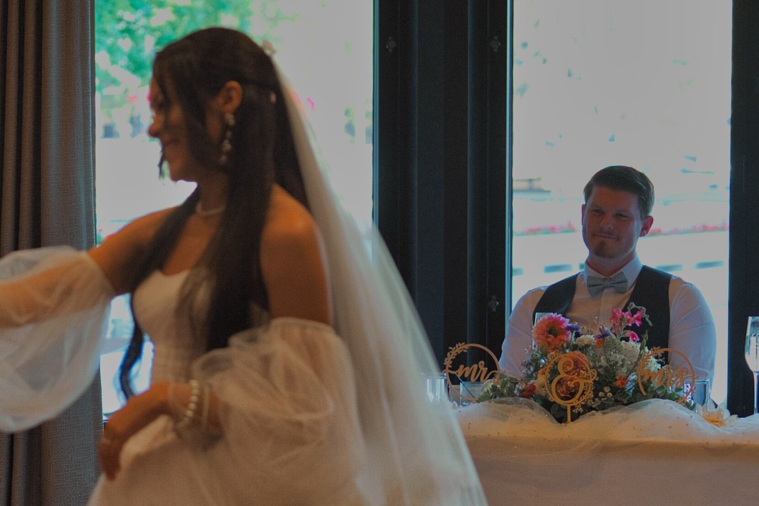 A picture focusing on the groom watching his wife while she dances with her father during the father-daughter dance.